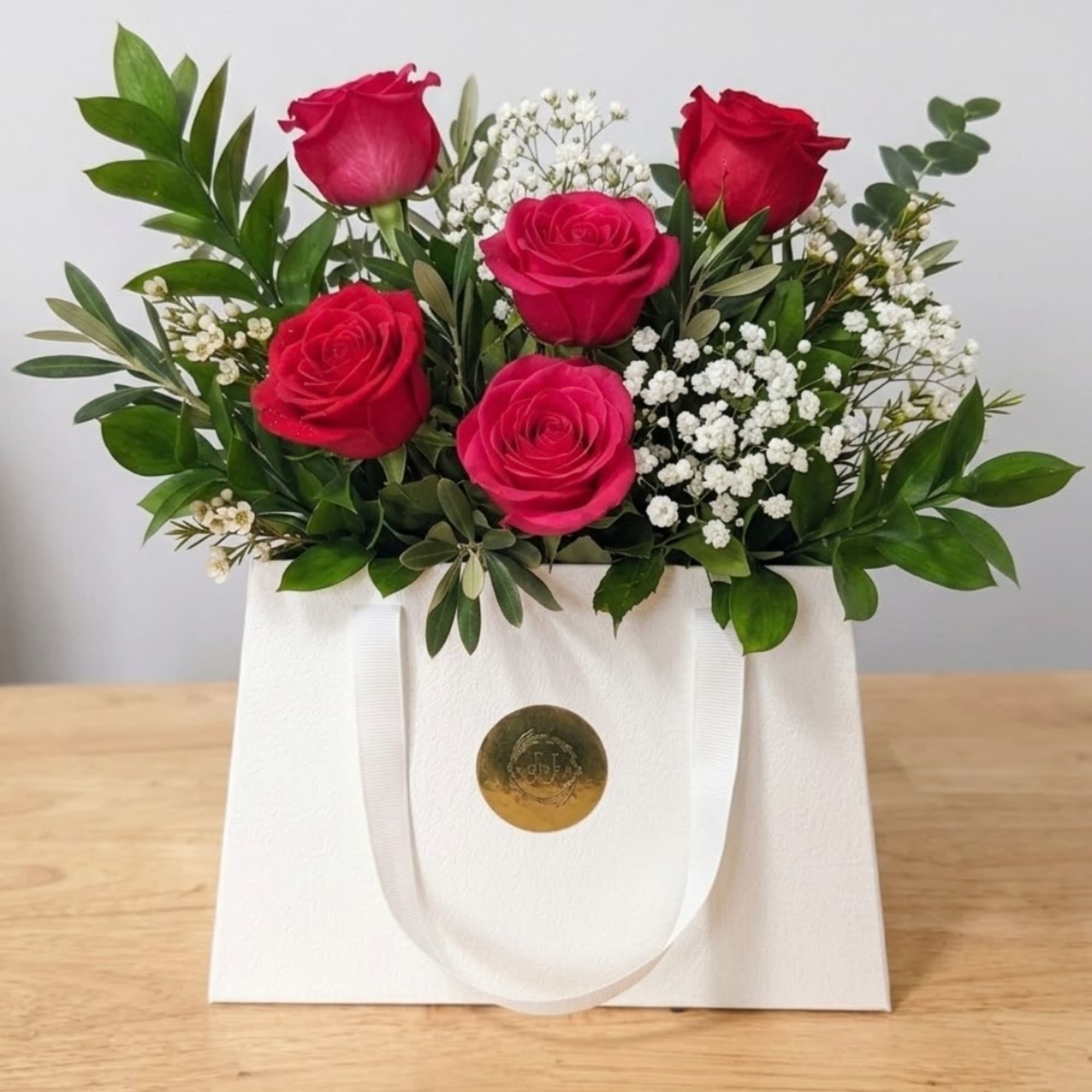 Pink and red roses with baby's breath in a white gift bag
