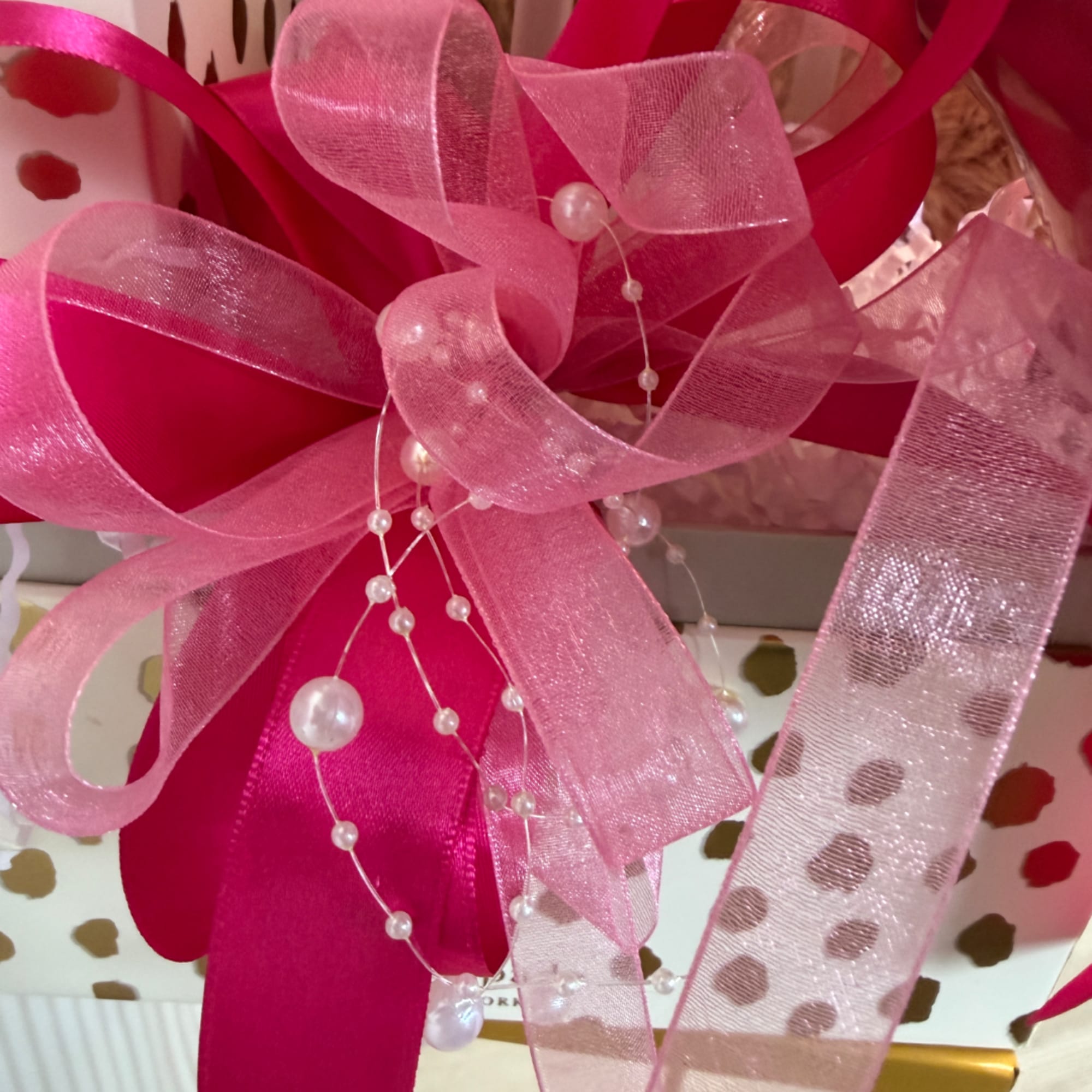 Pink ribbon bow with pearl strands on a gift box