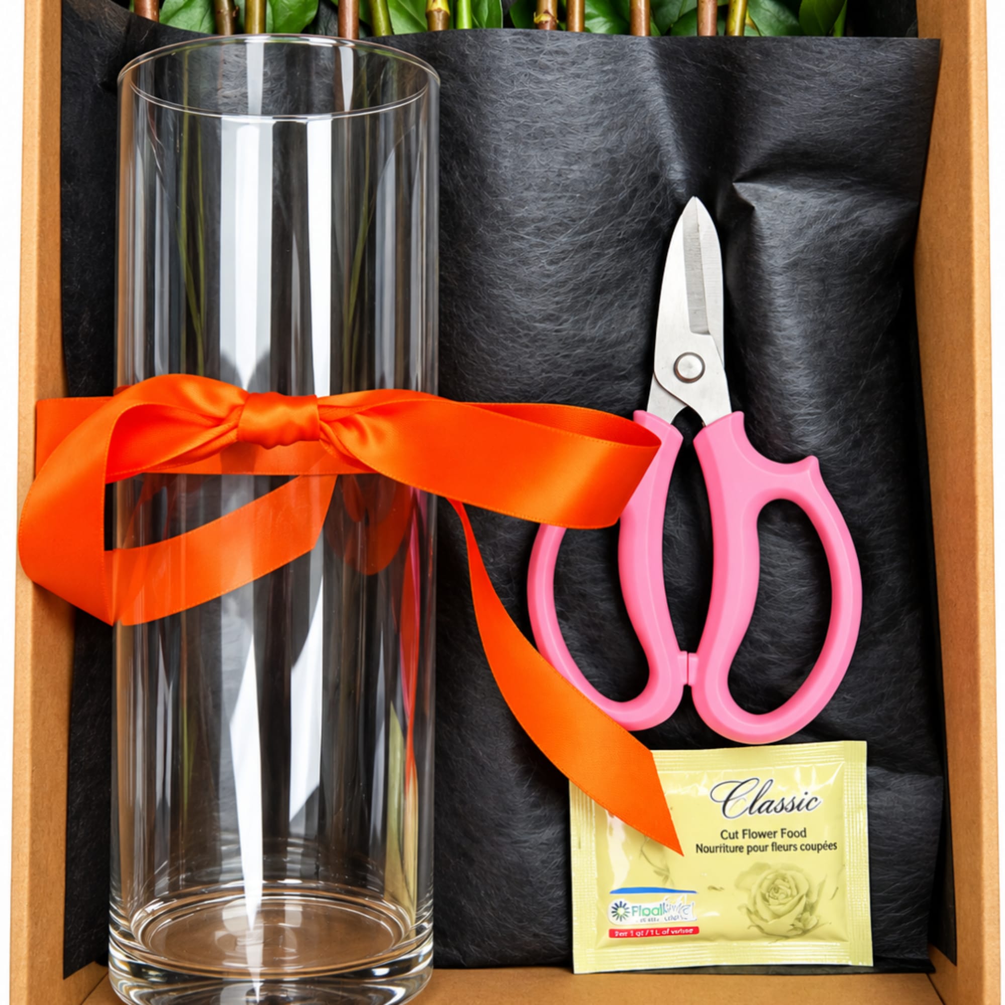 Glass vase with pink-handled scissors, ribbon, and flower food packet