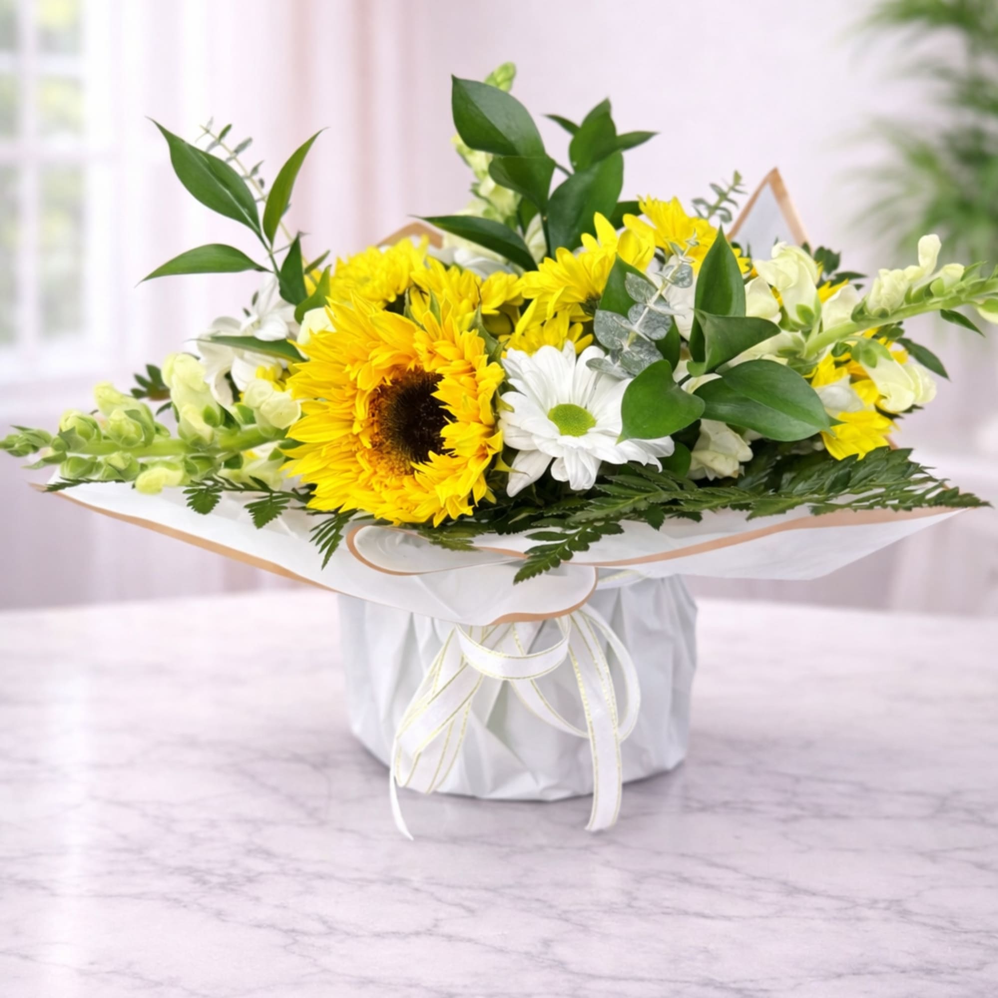 Yellow sunflowers and white daisies in a wrapped bouquet box