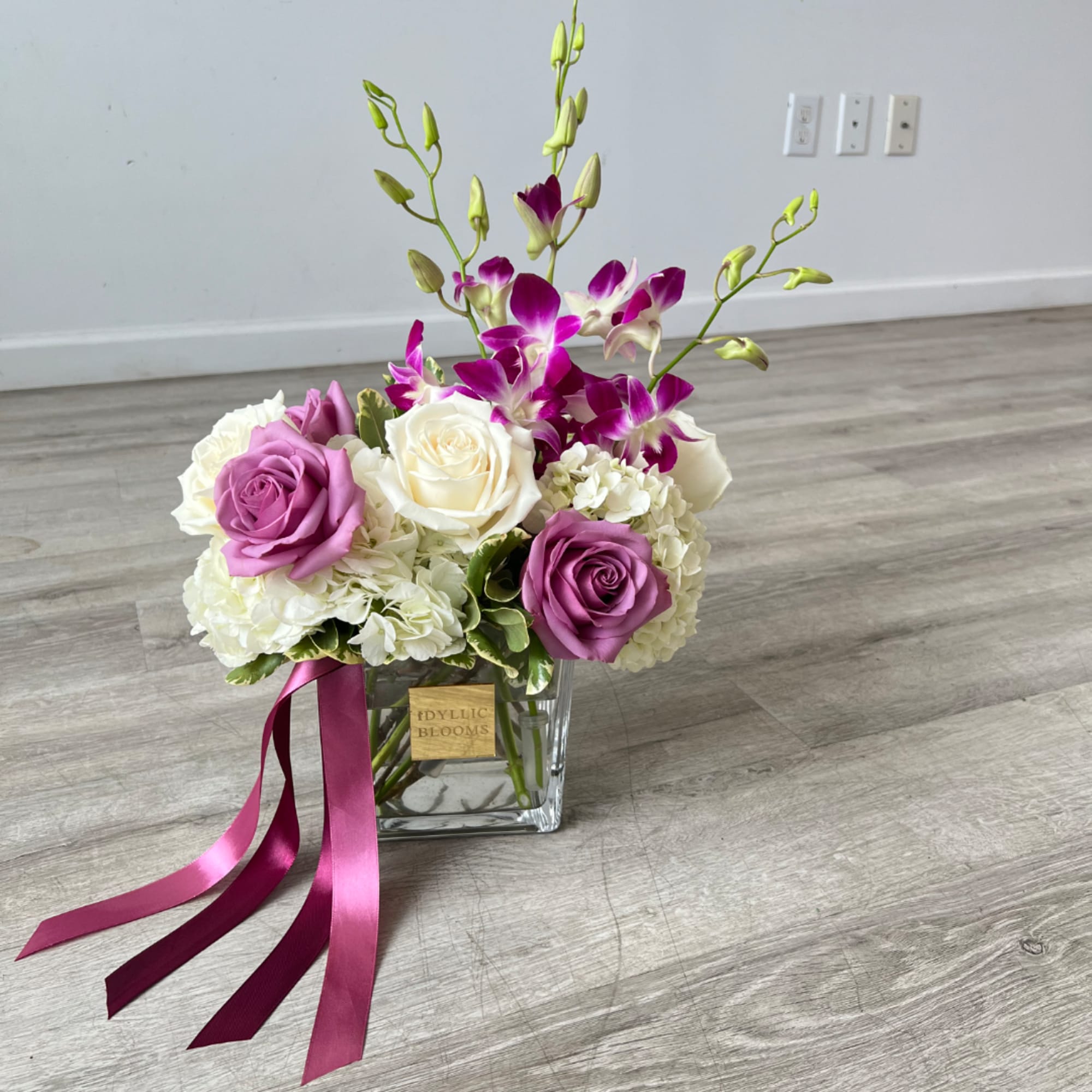 Pink and white roses with purple orchids in a glass vase