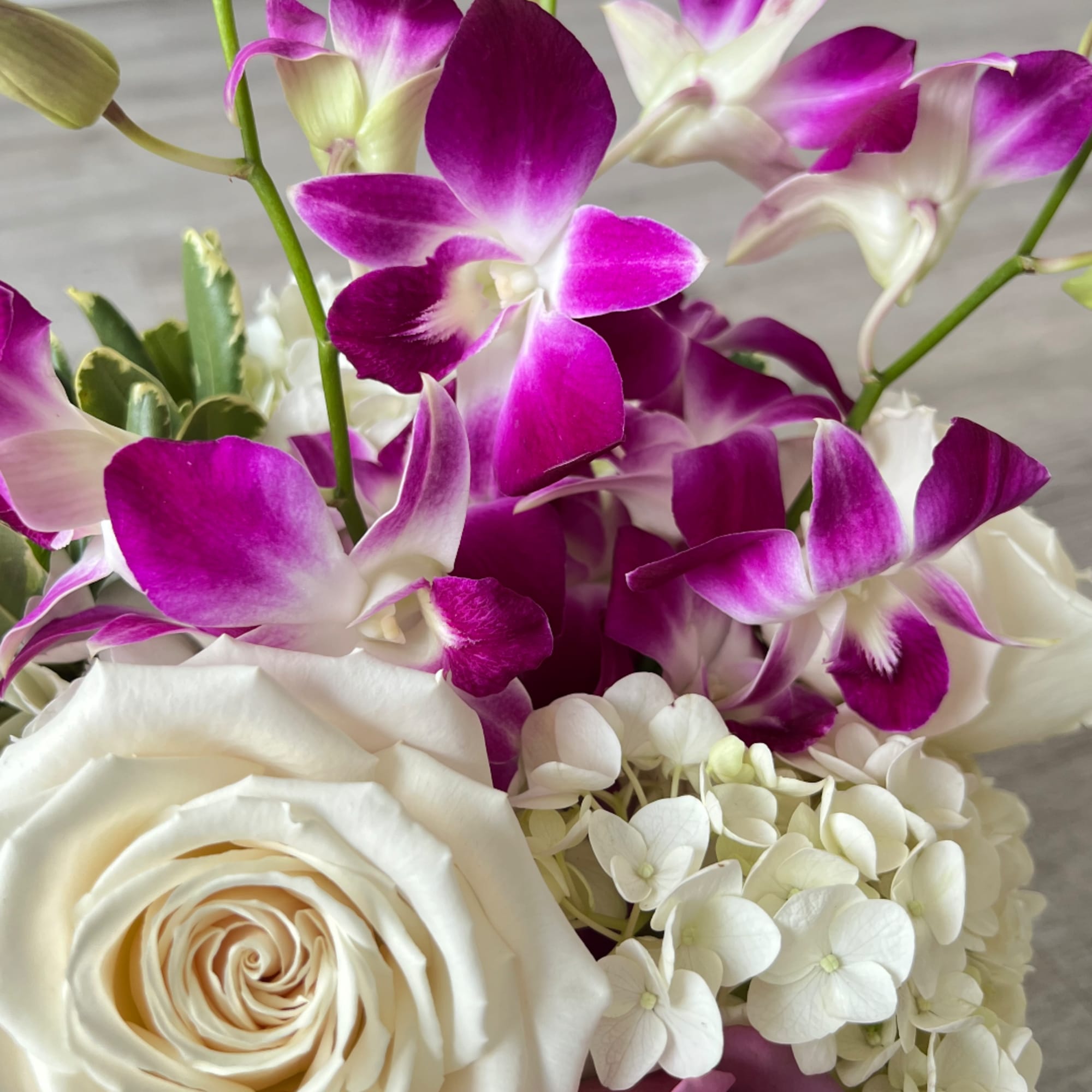 White roses and purple orchids with white hydrangea blooms in a bouquet
