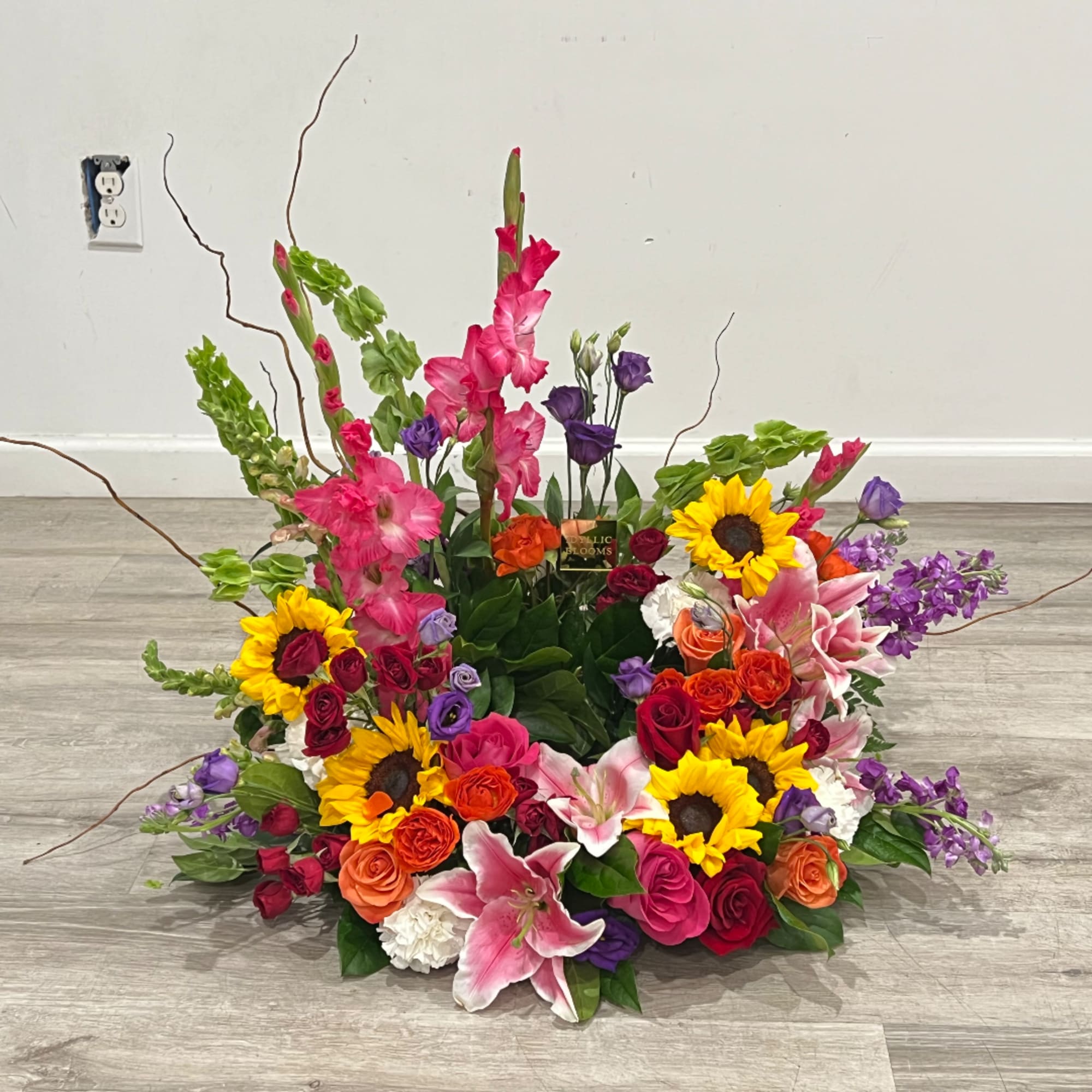 Large mixed flower arrangement with sunflowers, roses, lilies, and pink gladiolus