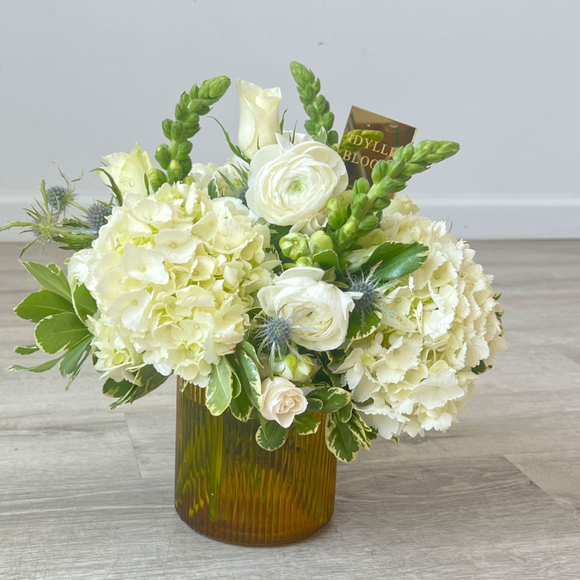 White floral arrangement in an amber glass vase with green accents