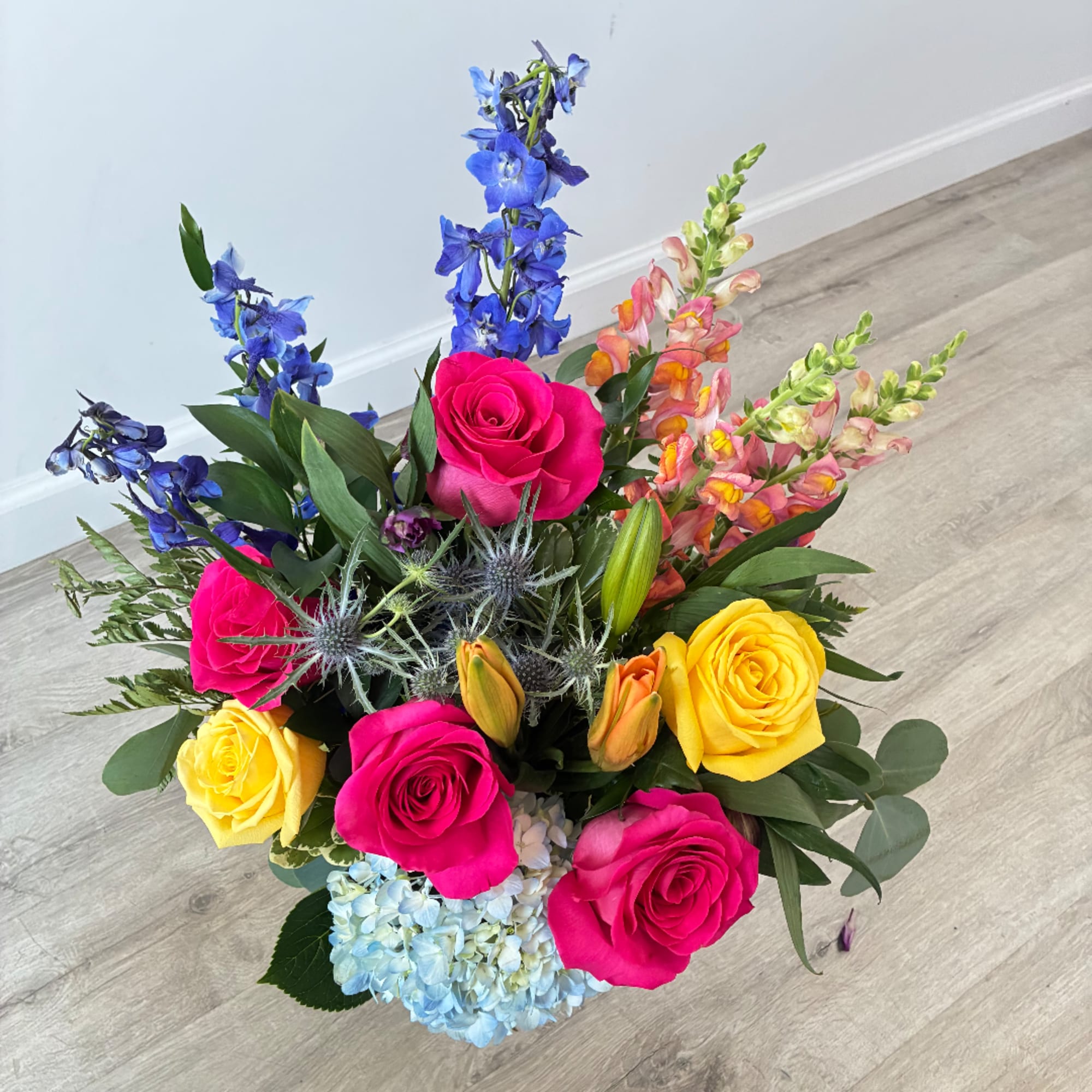 Bright mixed bouquet with pink and yellow roses, blue flowers, and hydrangea