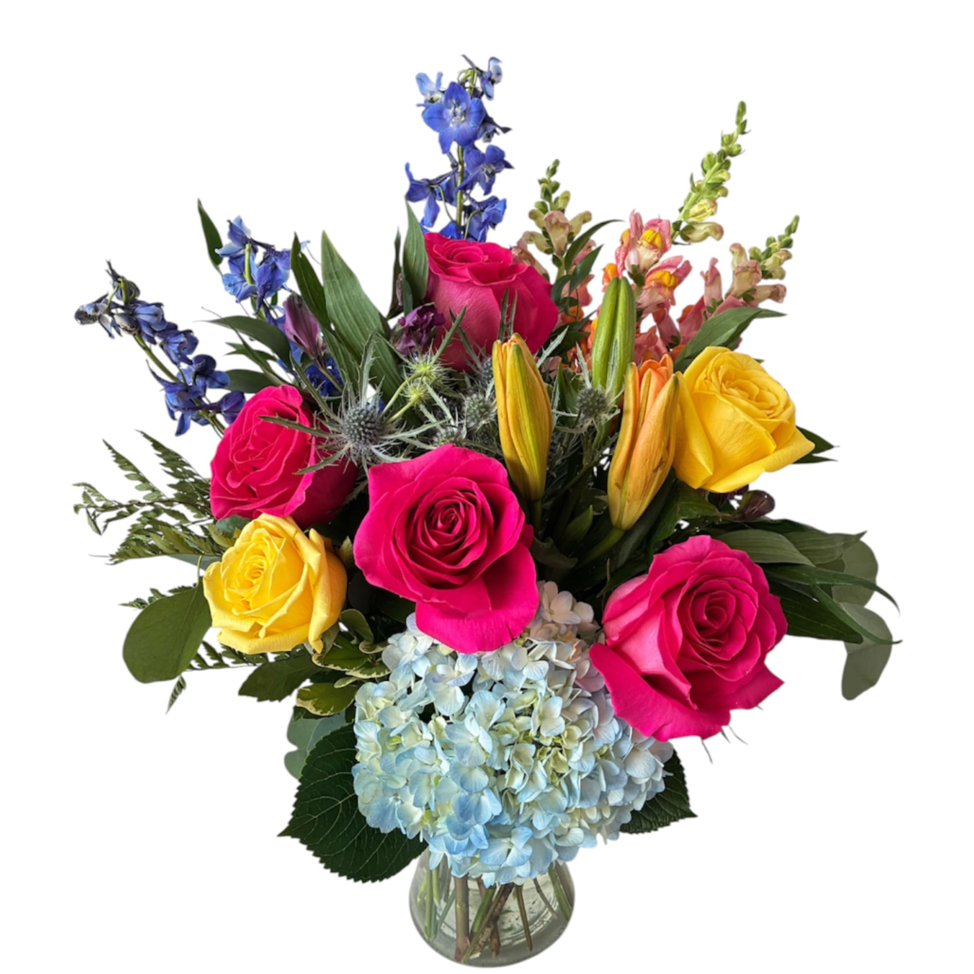 Bright mixed bouquet of roses, lilies, and blue hydrangea in a glass vase