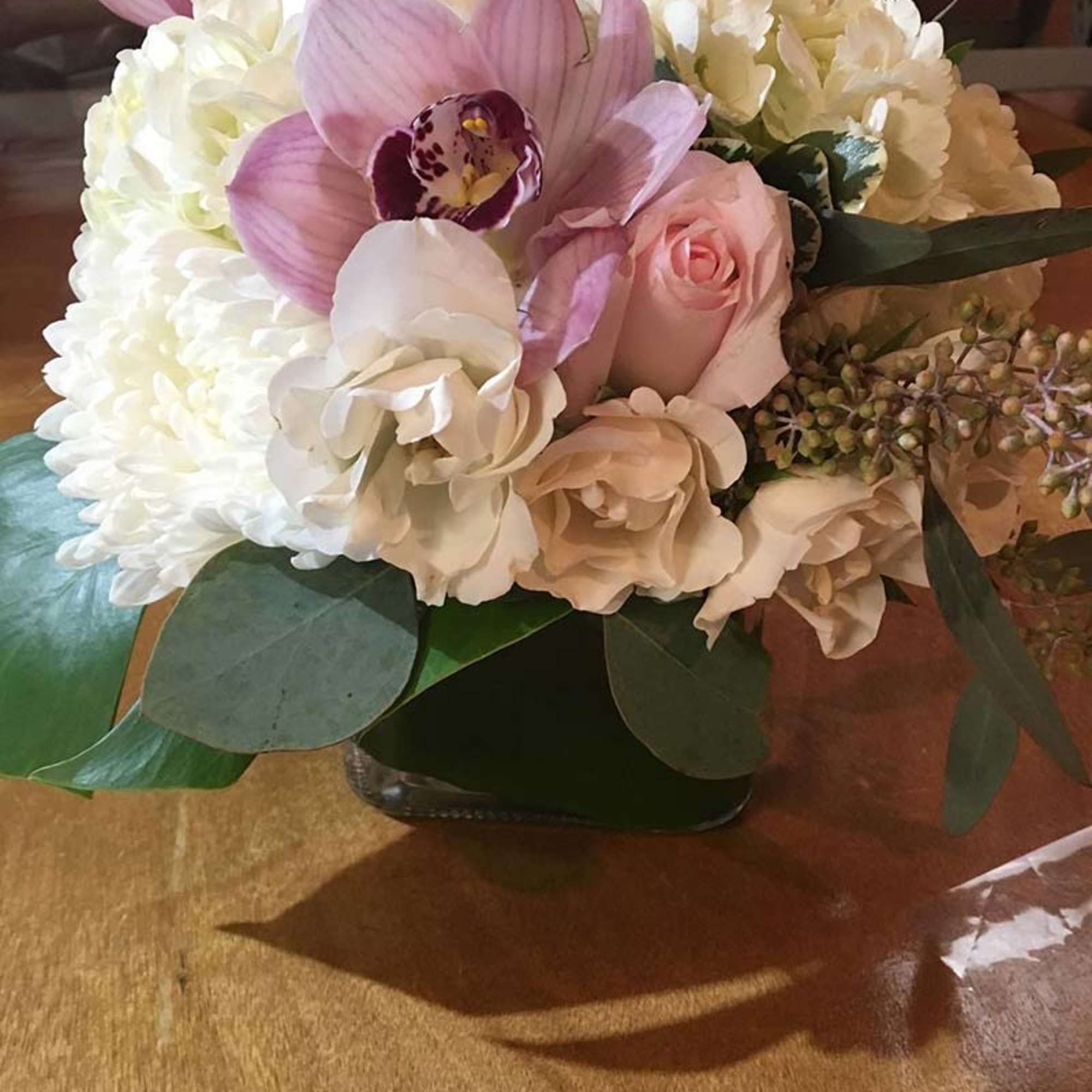 Pink and white bouquet with orchids, roses, and hydrangeas in a low vase