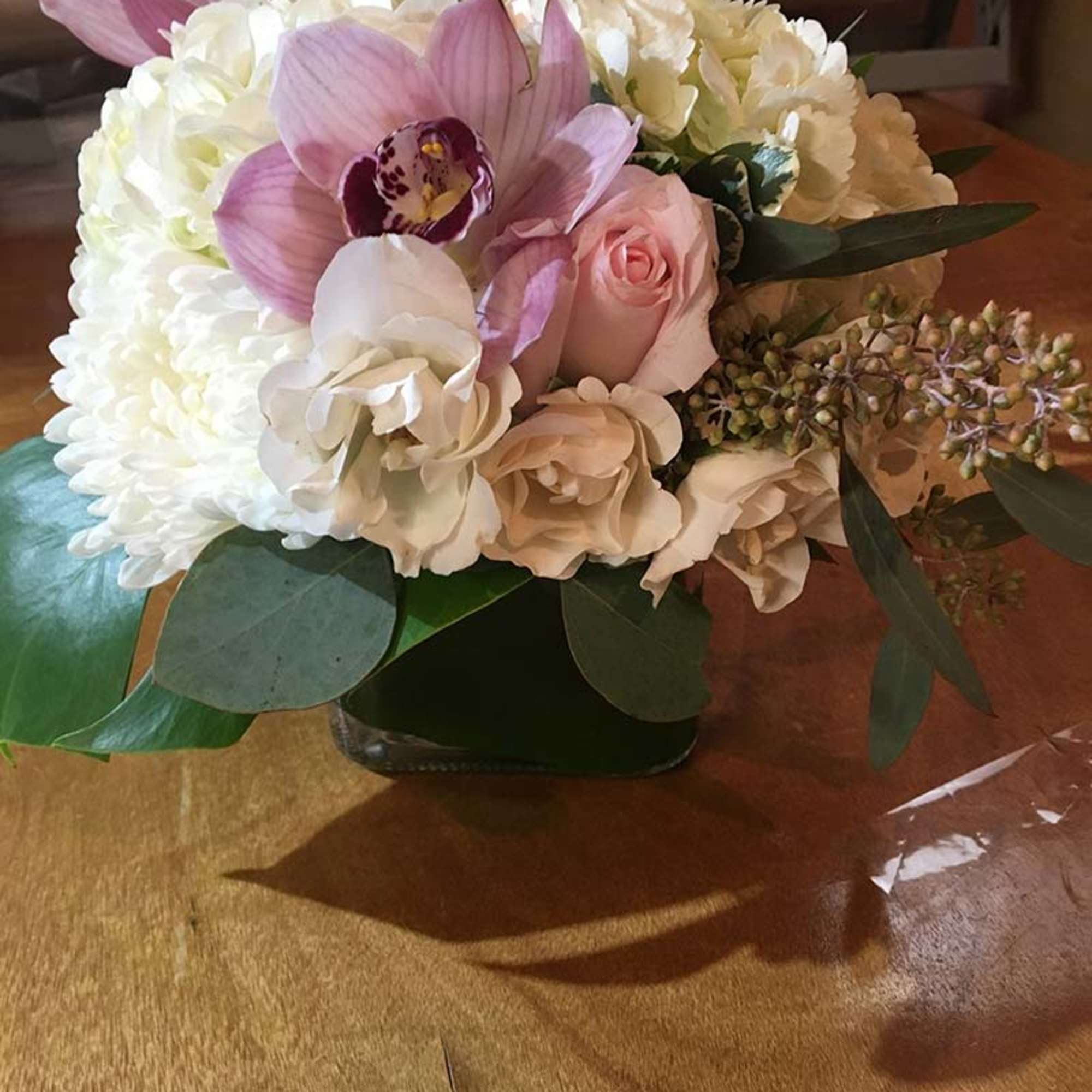Pink orchid and roses in a low glass vase with white blooms