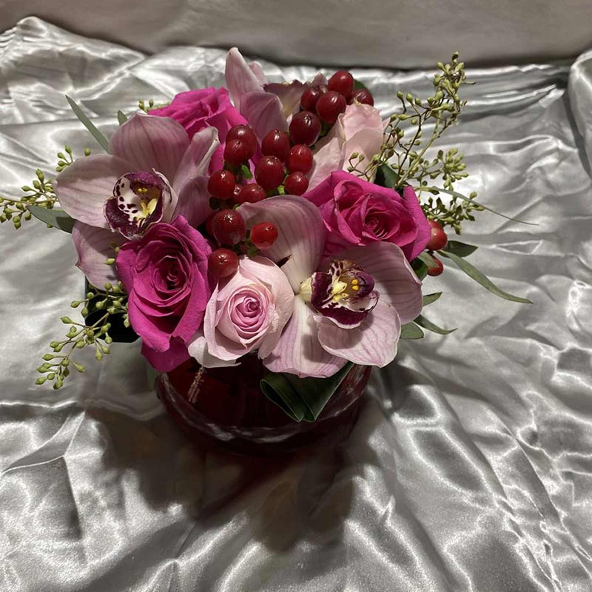 Pink roses and orchids arranged in a red vase