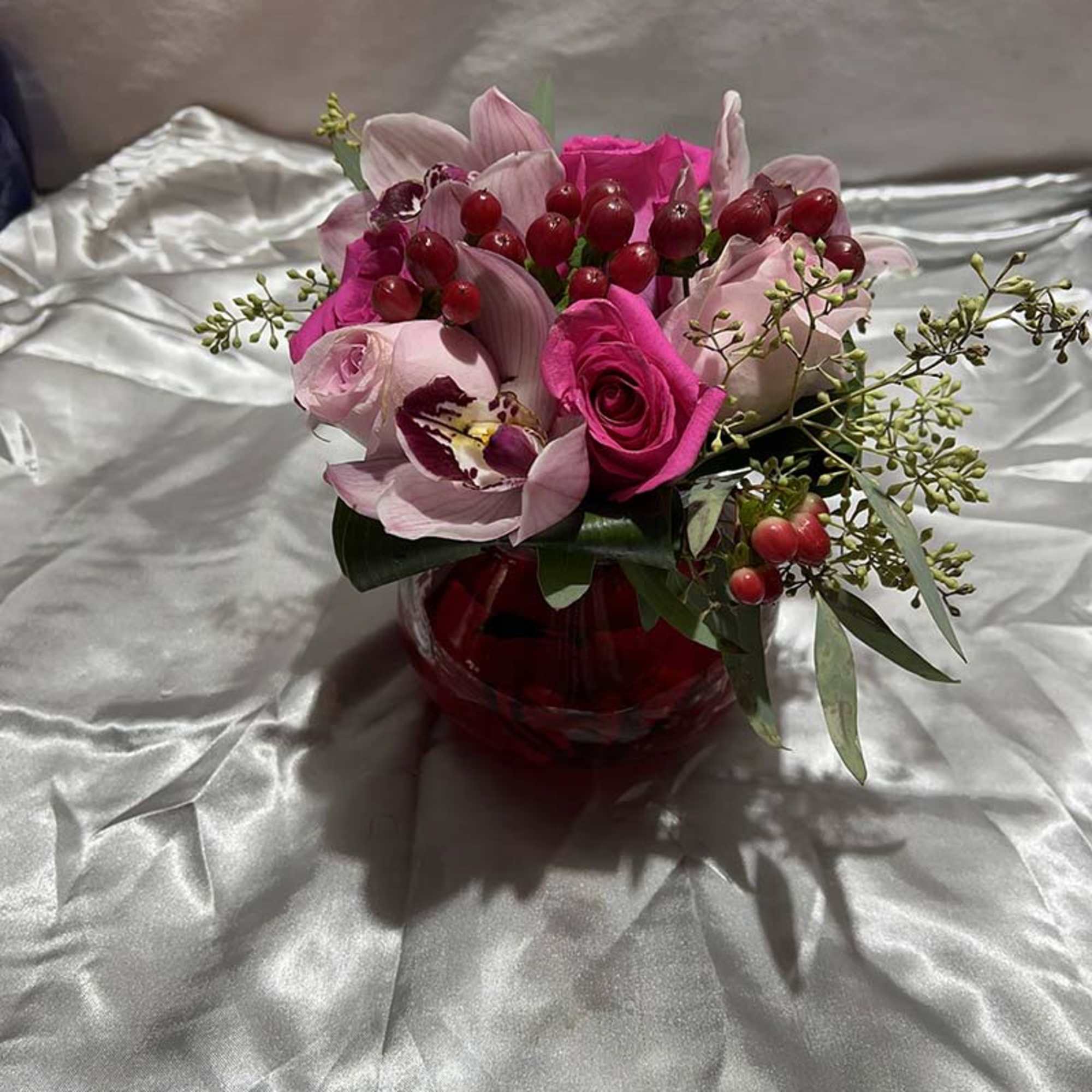 Pink and white floral arrangement in a red glass vase