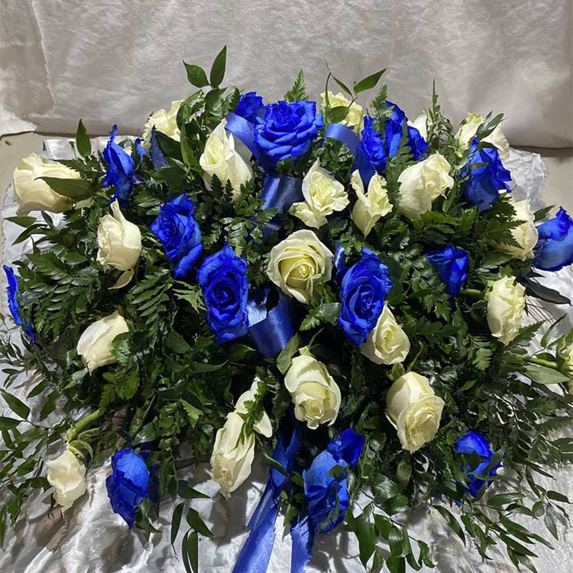 Blue and white rose arrangement with ribbon on satin fabric