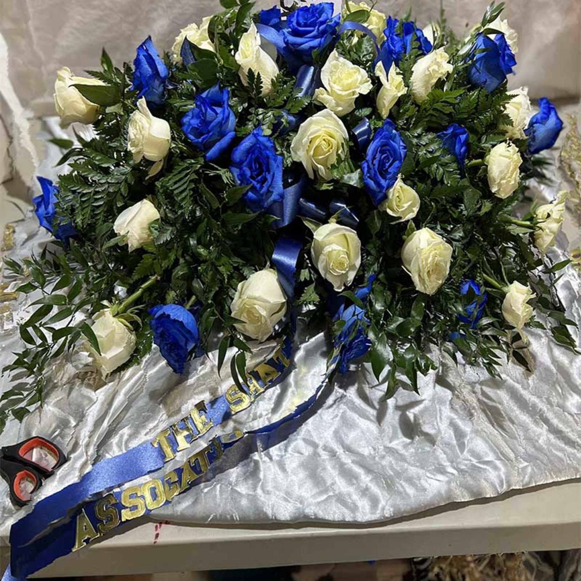Blue and white rose arrangement with a ribbon on satin fabric