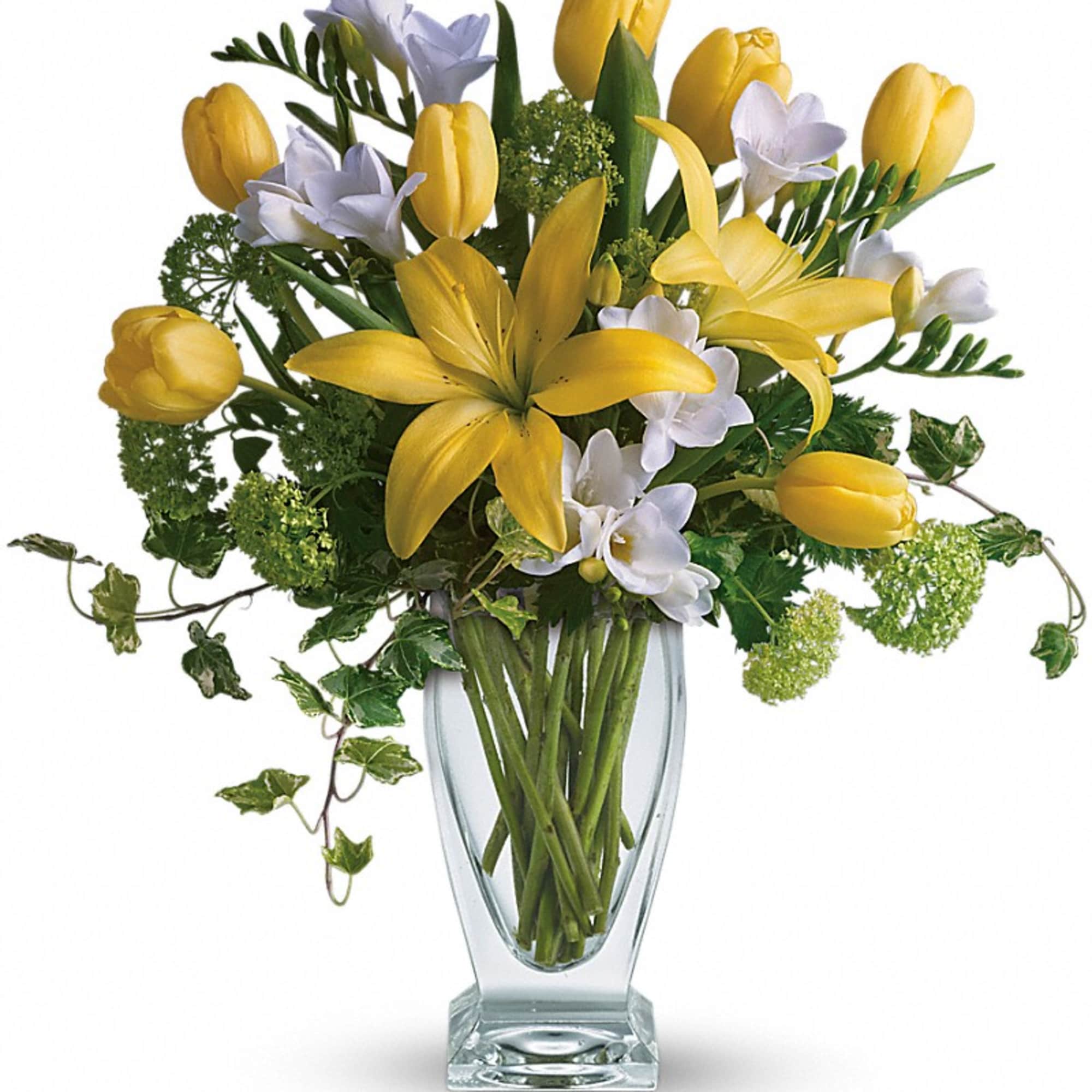 Yellow tulips and white freesia in a clear glass vase