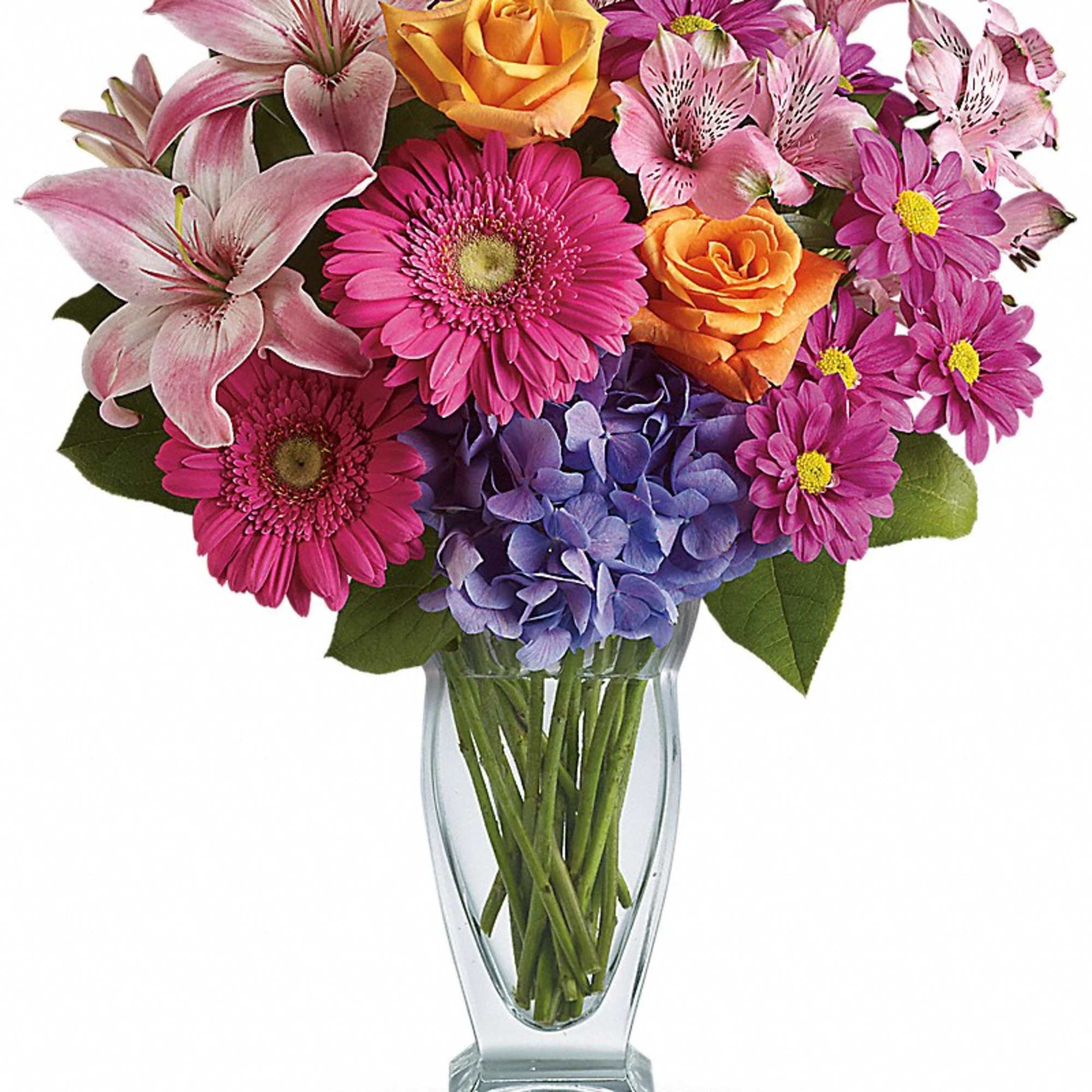Mixed bouquet of pink lilies, roses, daisies, and blue hydrangea in a glass vase