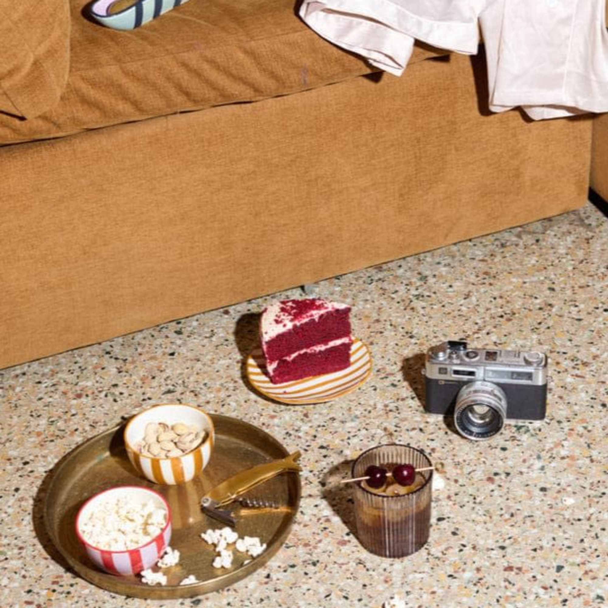 Assorted snacks and a slice of cake on the floor beside a couch