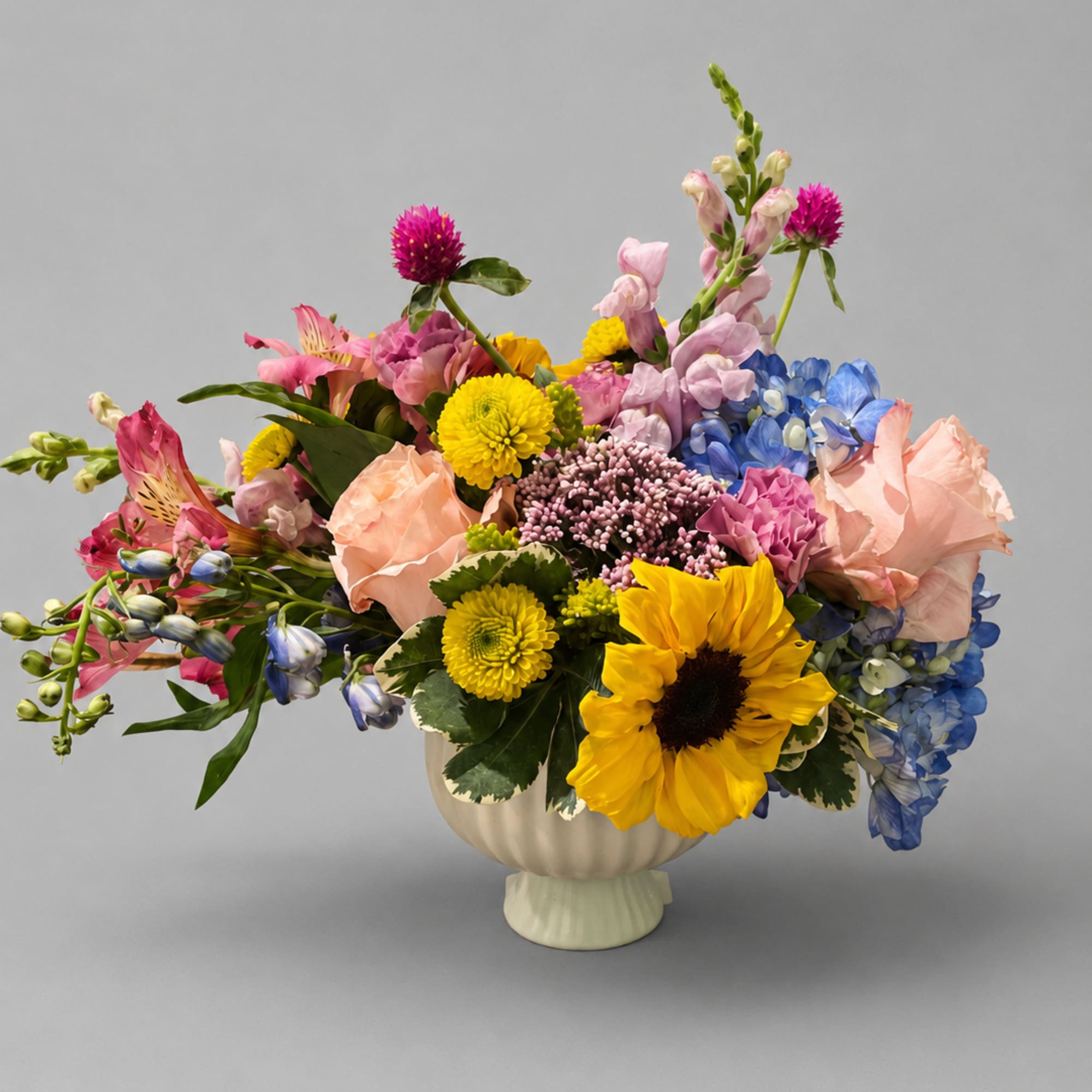 Colorful mixed flower arrangement in a cream vase