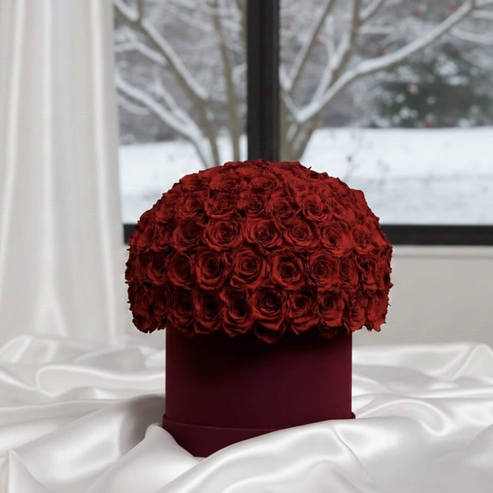 Red rose dome in a burgundy box on white satin