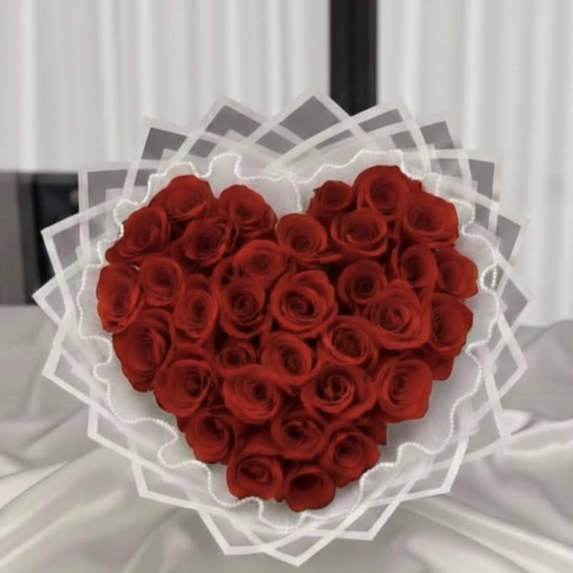 Heart-shaped bouquet of red roses wrapped in white paper