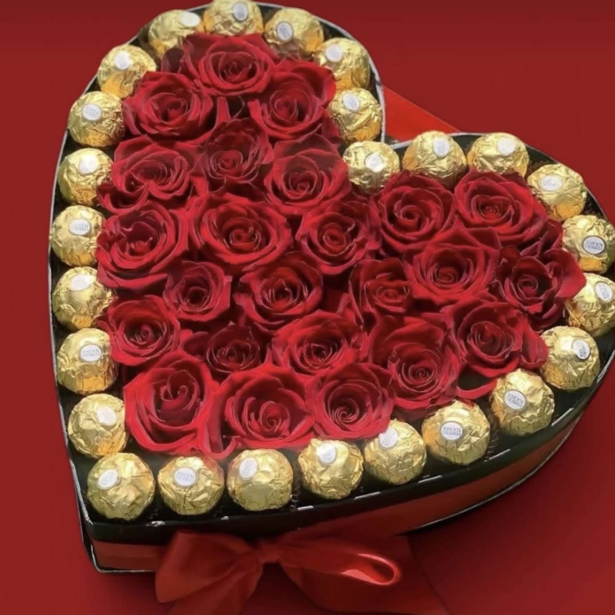 Heart-shaped box of red roses surrounded by gold-wrapped chocolates