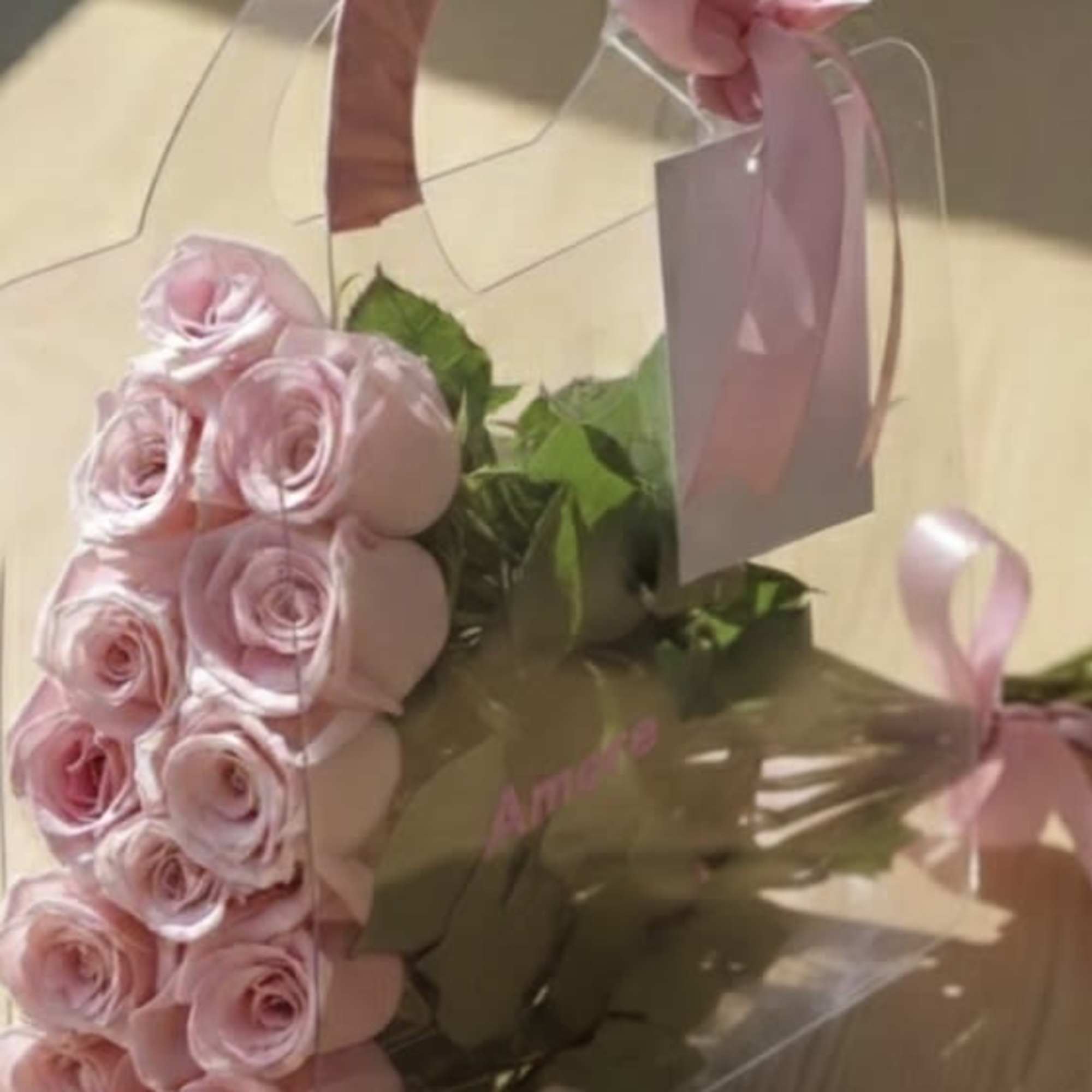 Pink roses in a clear gift box with a ribbon handle