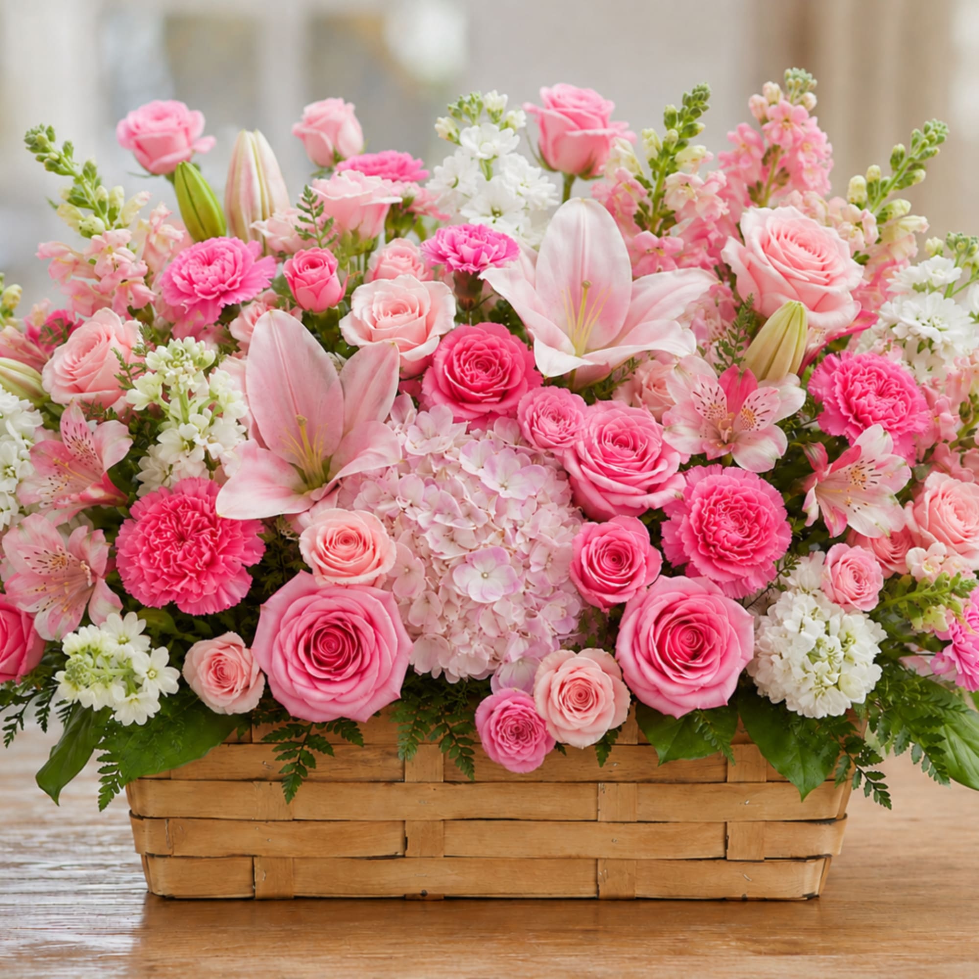 Pink roses, lilies, and carnations arranged in a woven basket