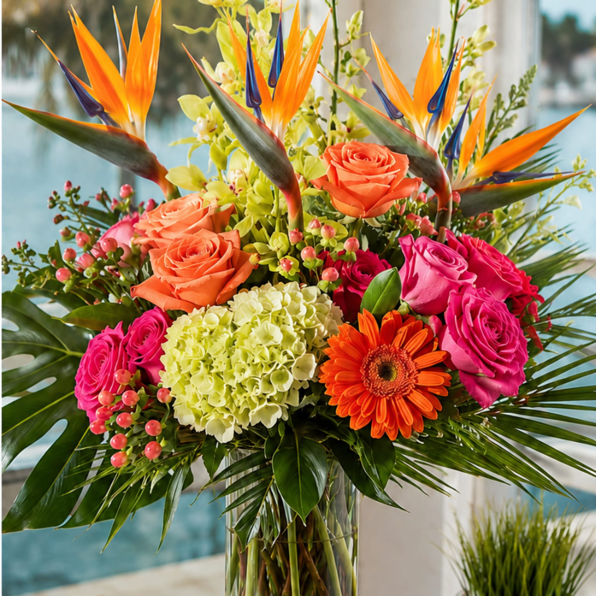 Tropical bouquet with roses, hydrangea, gerbera daisies, and bird of paradise in a glass vase
