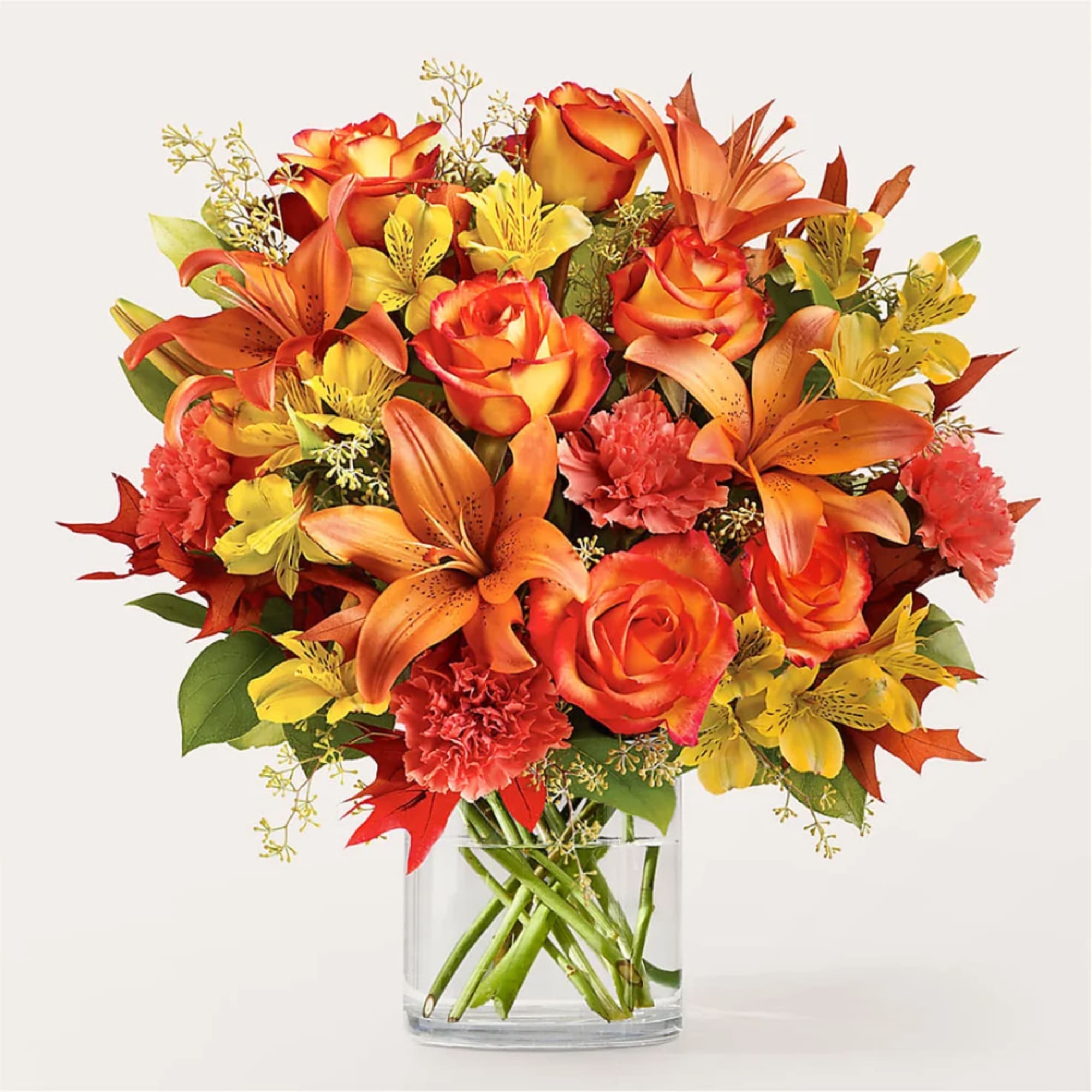 Bouquet of orange roses, lilies, and carnations in a clear glass vase
