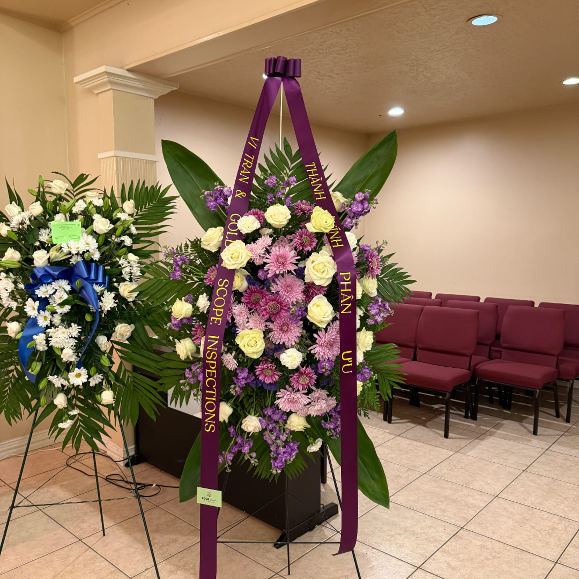 Standing floral wreath with purple ribbon and mixed white and purple flowers