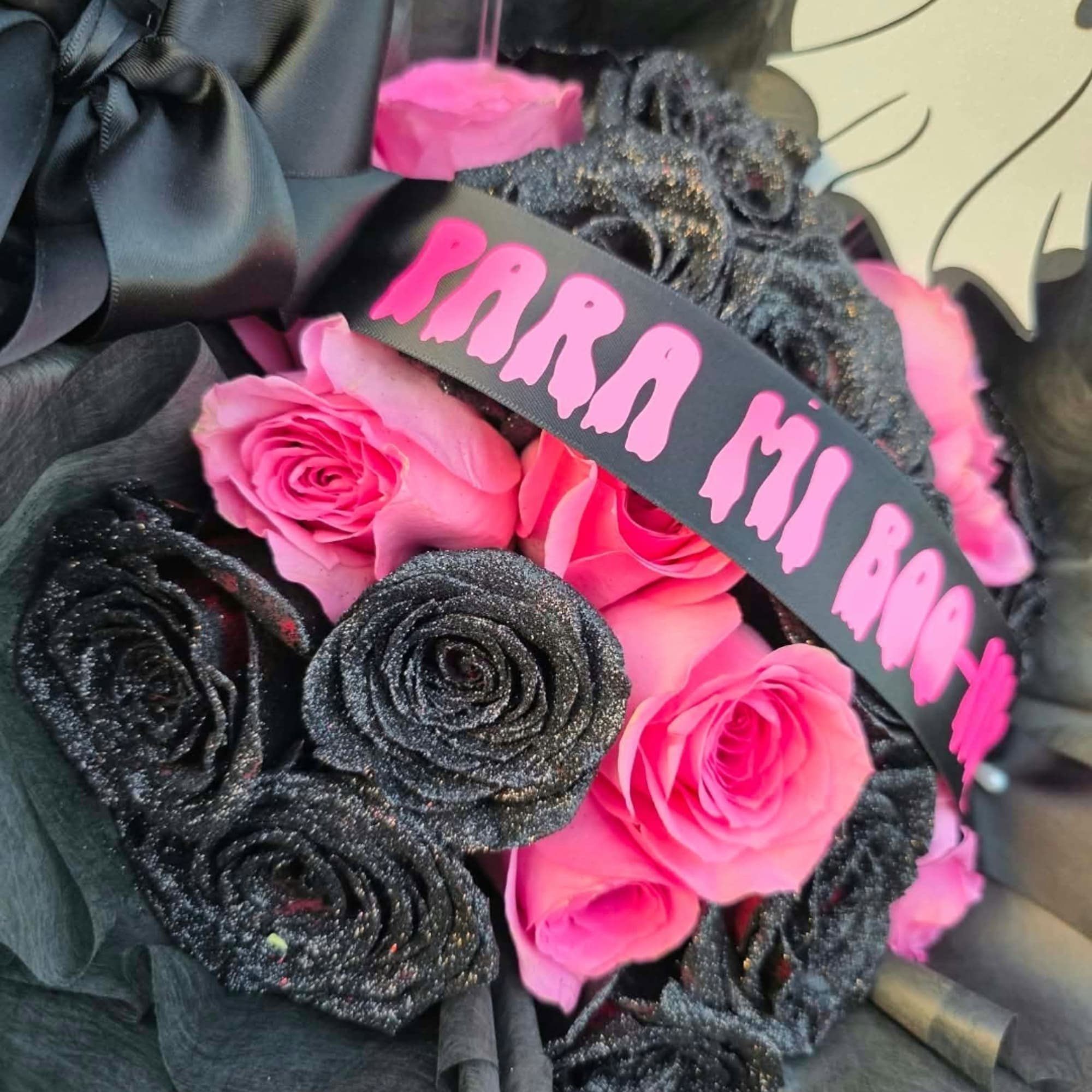 Pink and black rose bouquet with a ribbon reading "PARRA MI RO"
