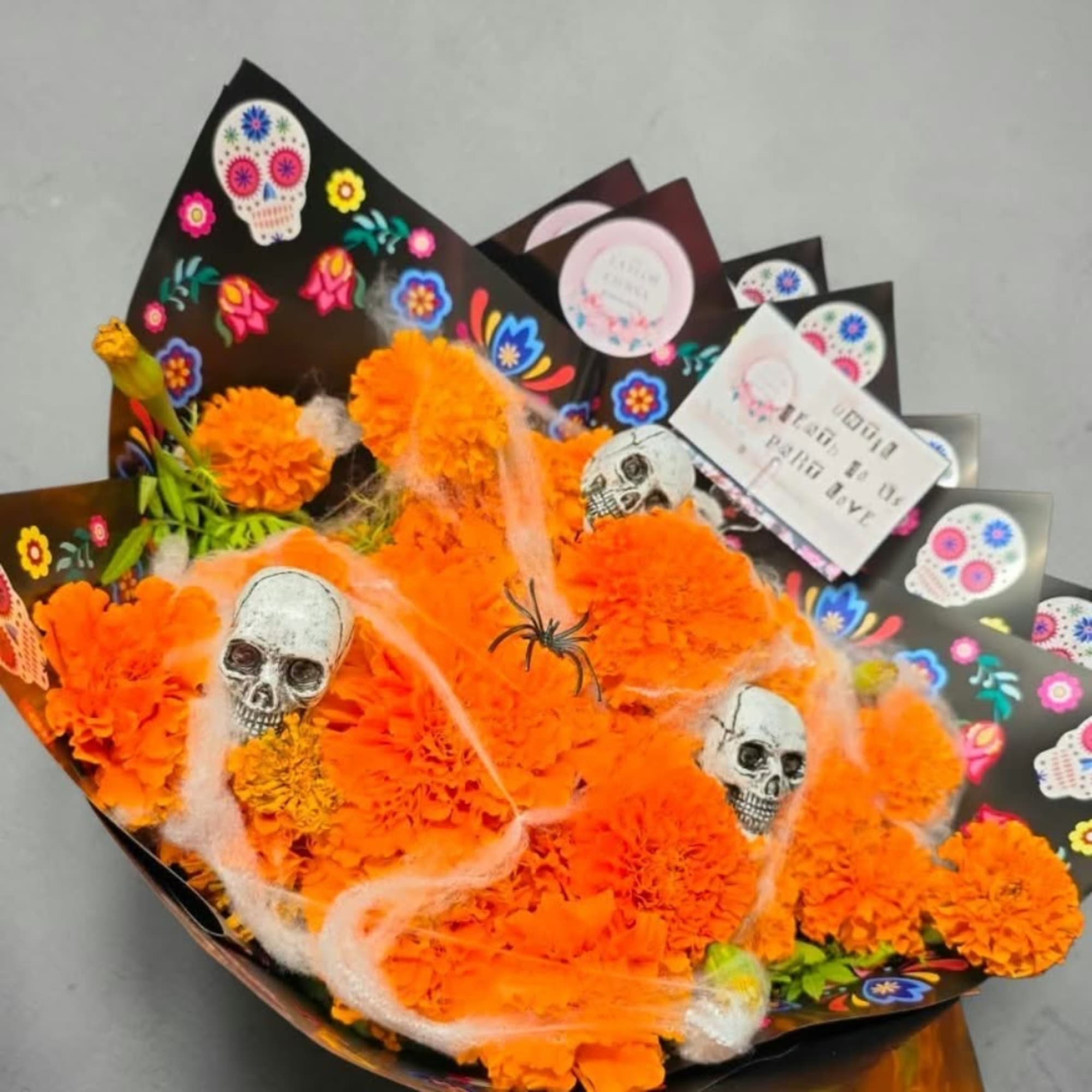 Orange marigold bouquet with skull decorations and black wrapping