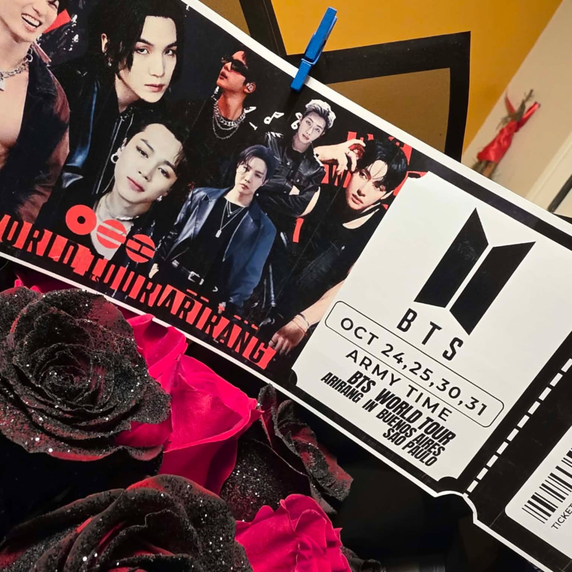 Black and pink roses beside a BTS poster and ticket graphic