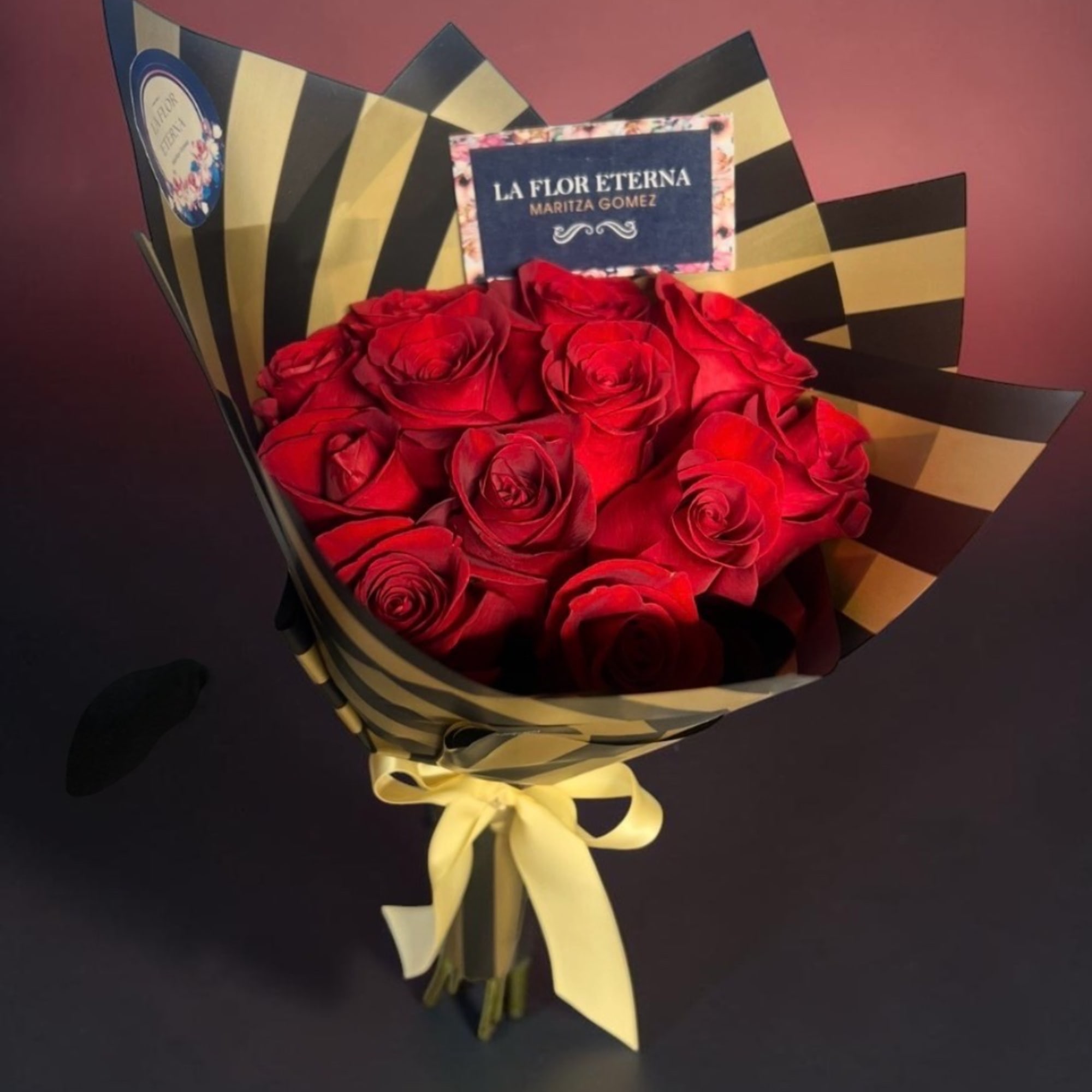 Bouquet of red roses wrapped in black and gold paper with a yellow ribbon