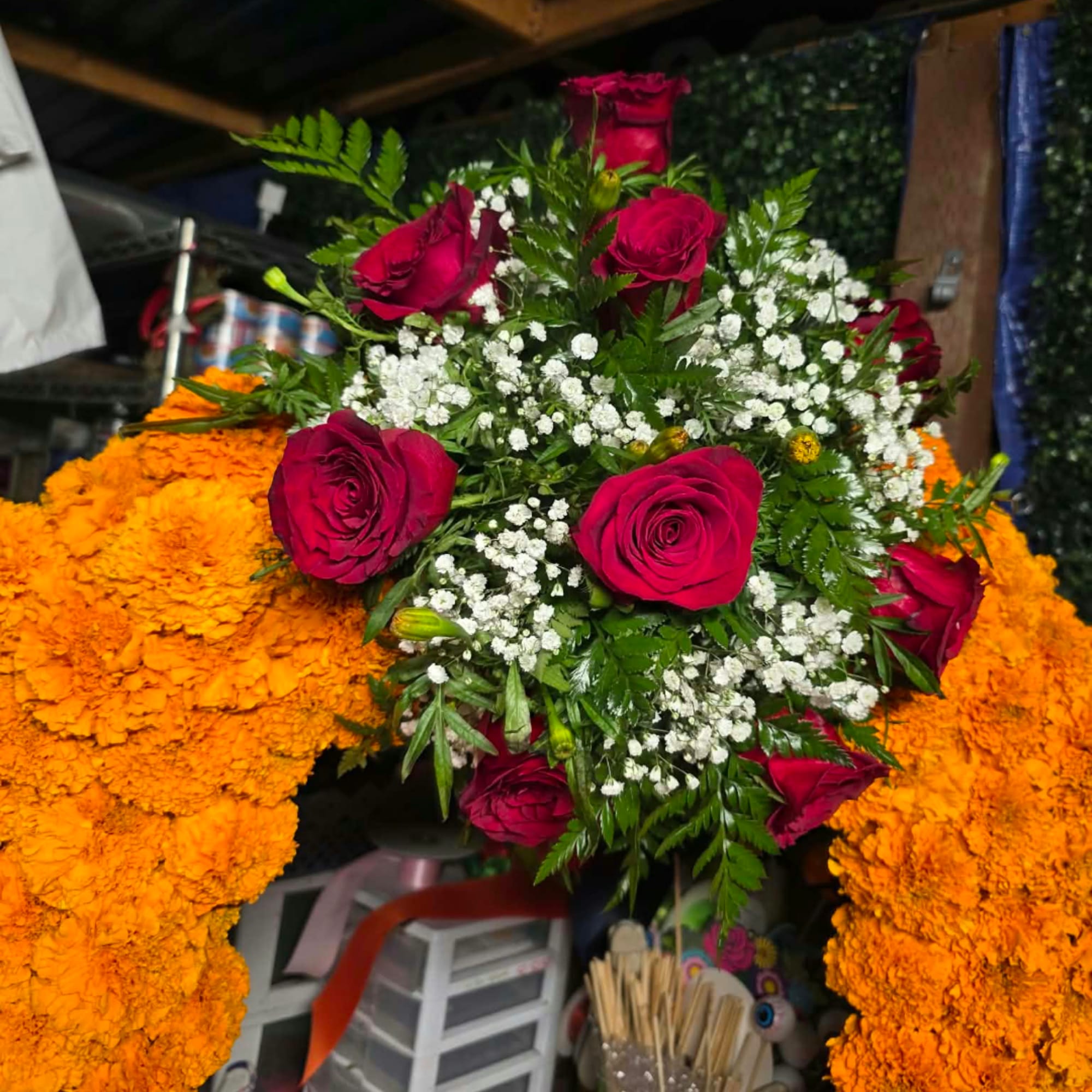 Red roses and white baby's breath arranged over orange marigold garlands