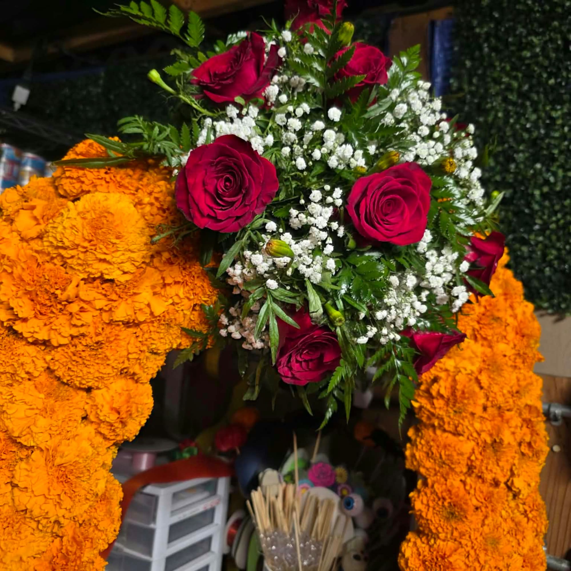 Large floral arrangement with red roses, white baby's breath, and orange marigold garlands