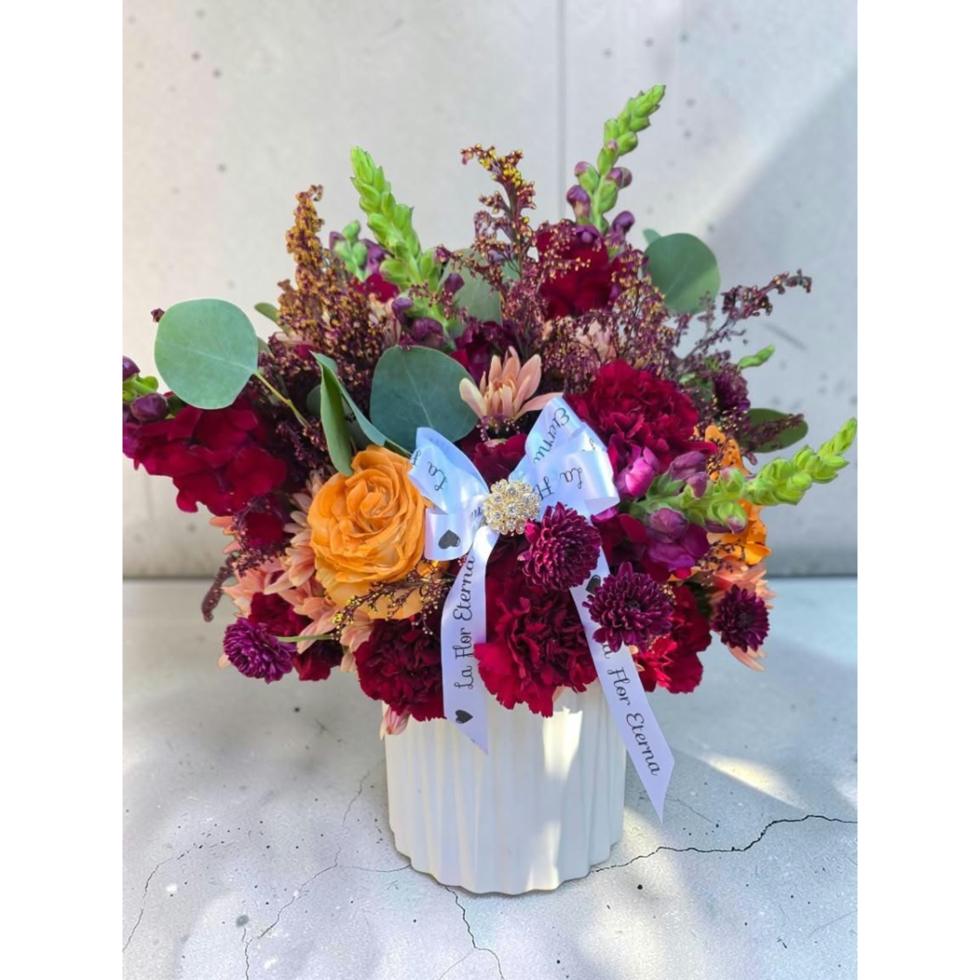 Colorful mixed bouquet in a white vase with ribbon accents