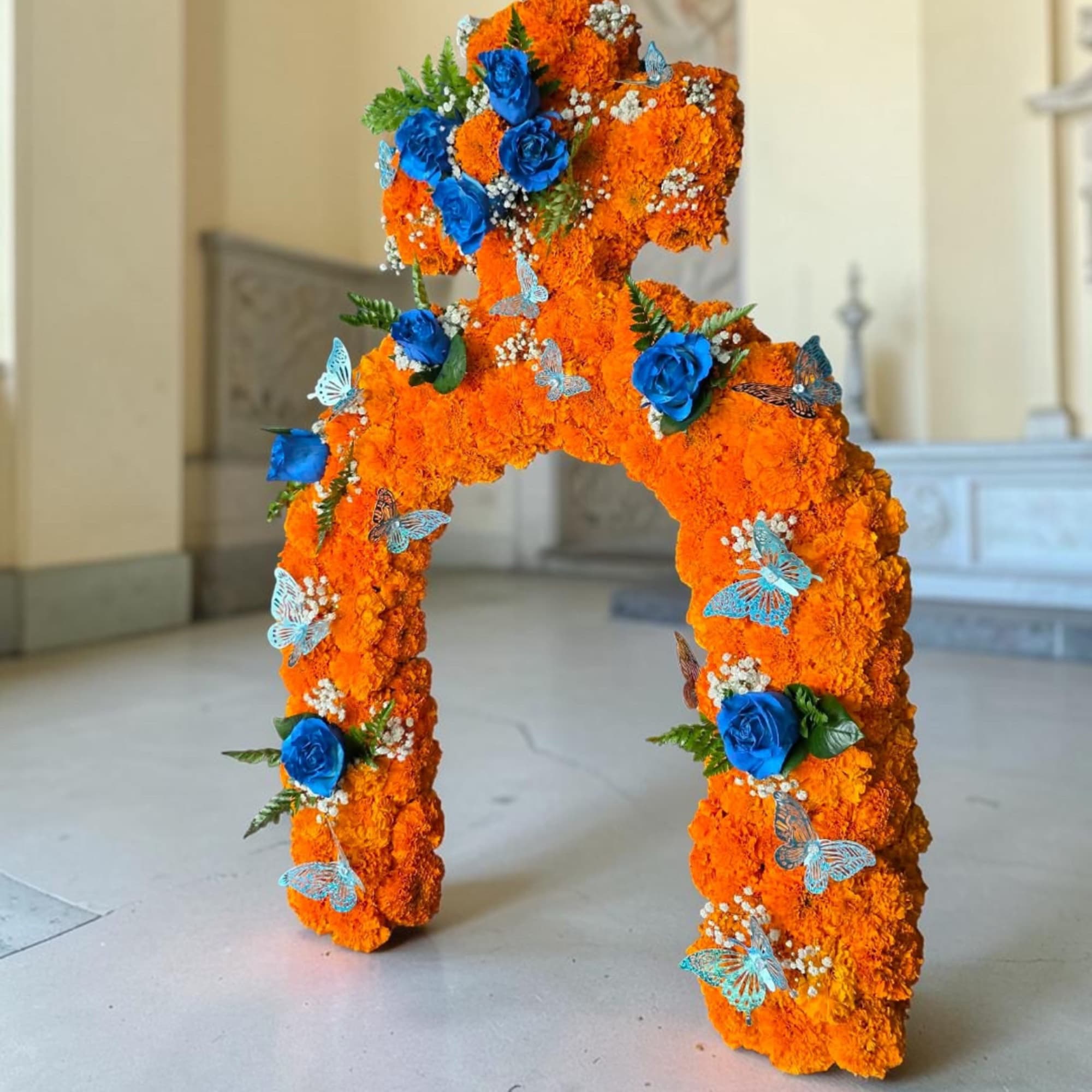 Orange floral arch with blue roses and butterfly accents
