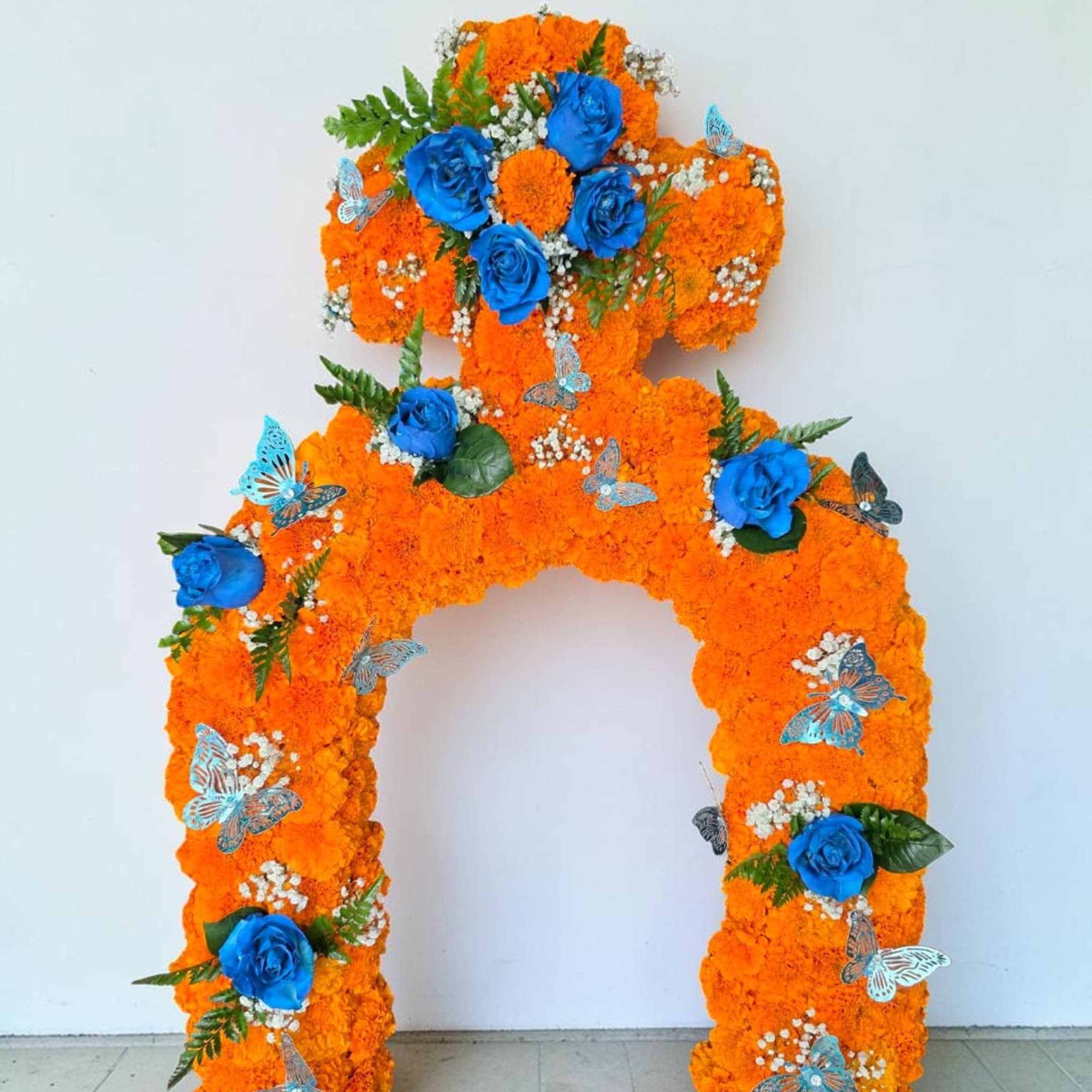 Orange floral arch with blue roses and butterfly accents, photo 2 of 6