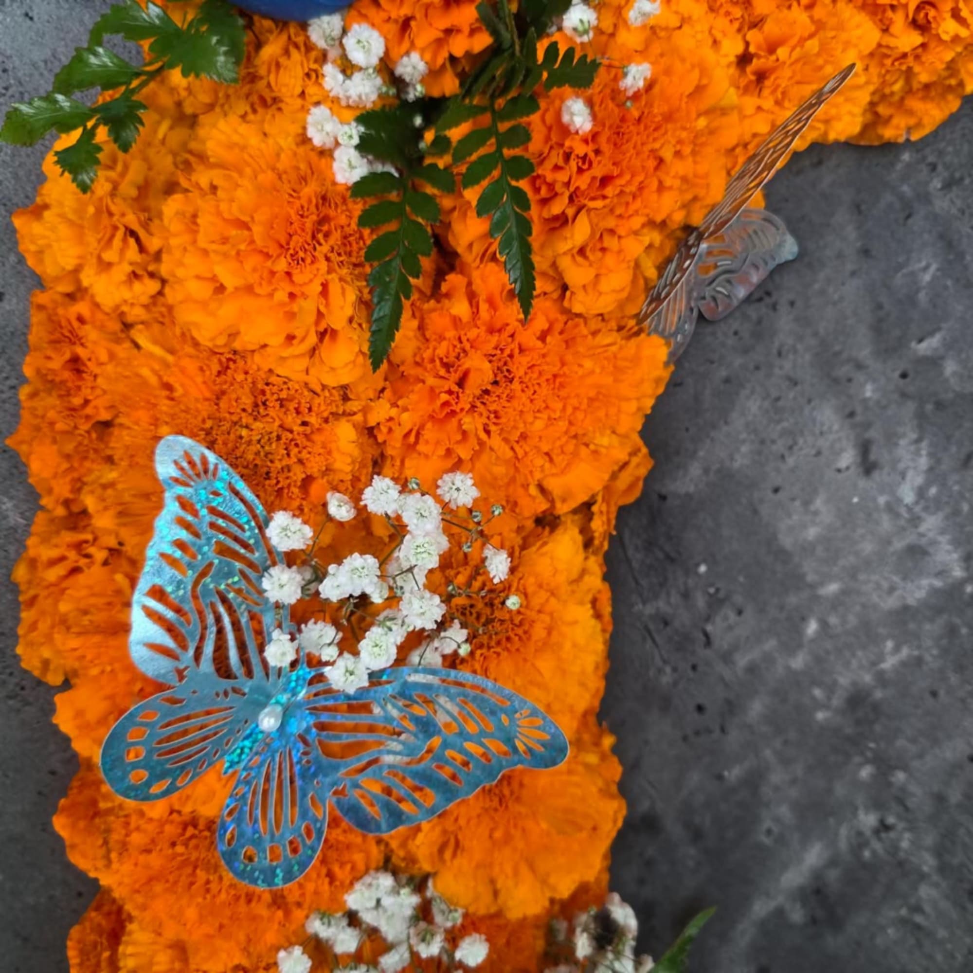 Orange marigold floral arrangement with white baby's breath and butterfly decorations