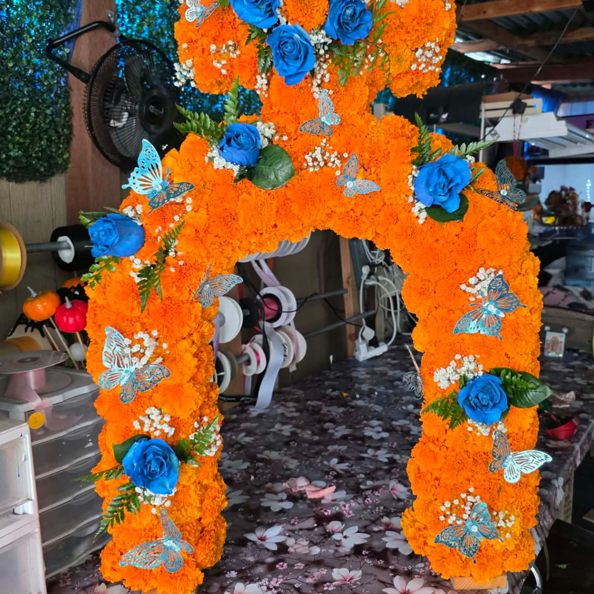 Orange floral arch with blue roses and butterfly decorations