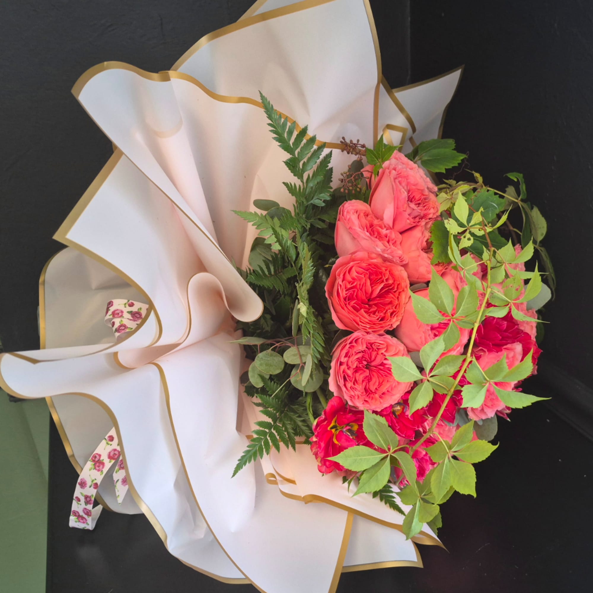 Pink rose bouquet wrapped in white paper with gold trim, photo 3 of 5