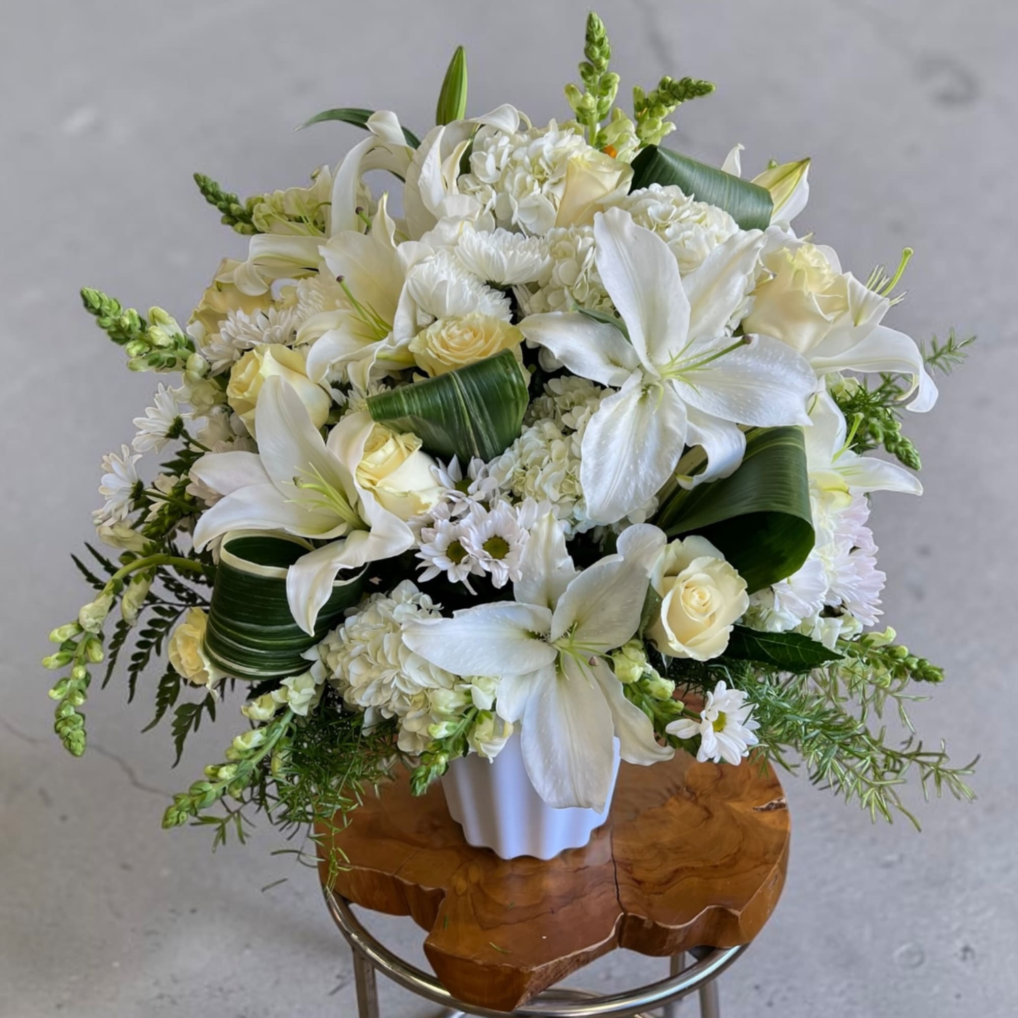 White lilies and roses arranged in a white vase