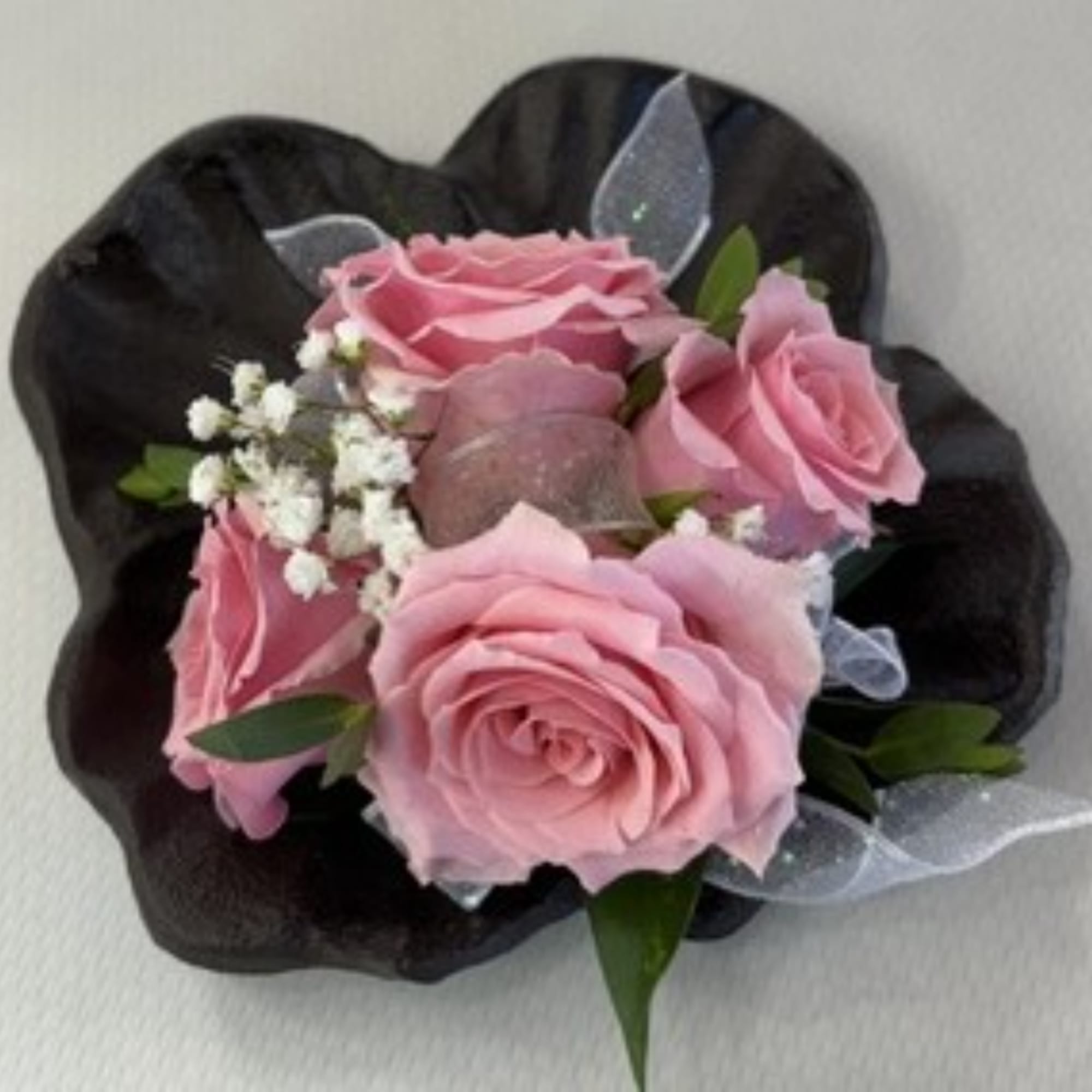 Pink rose bouquet wrapped in black paper with white filler flowers
