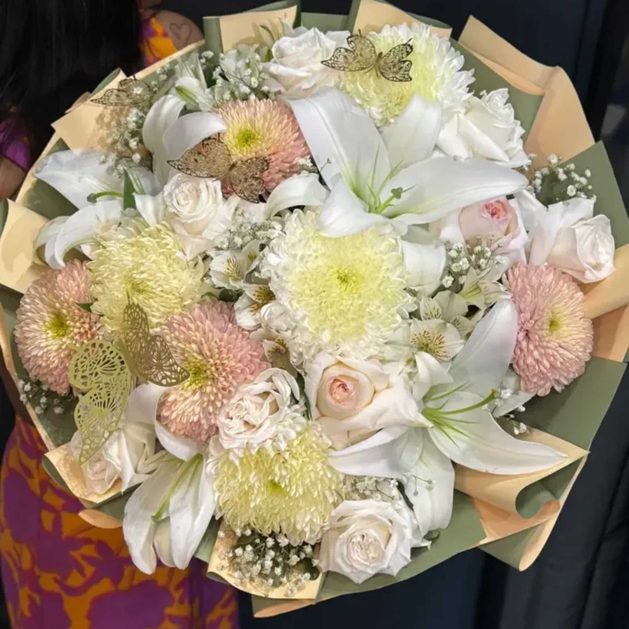 A soft dome of white lilies, creamy roses and pastel chrysanthemums greets