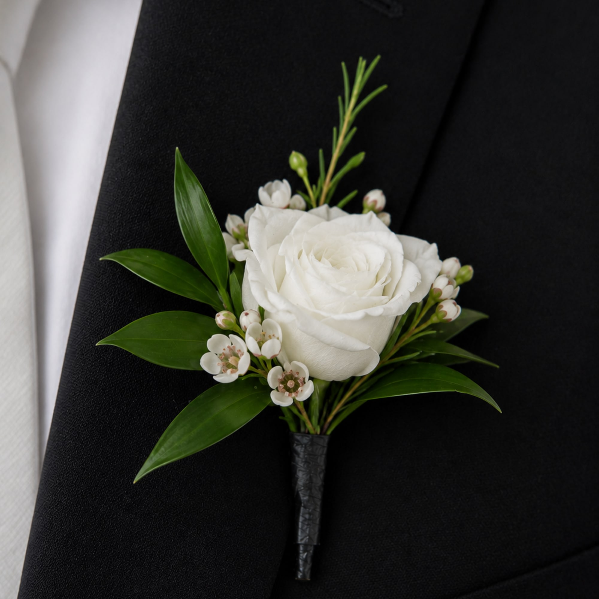 The Ivory Whisper Boutonniere is a sophisticated floral accessory designed for the
