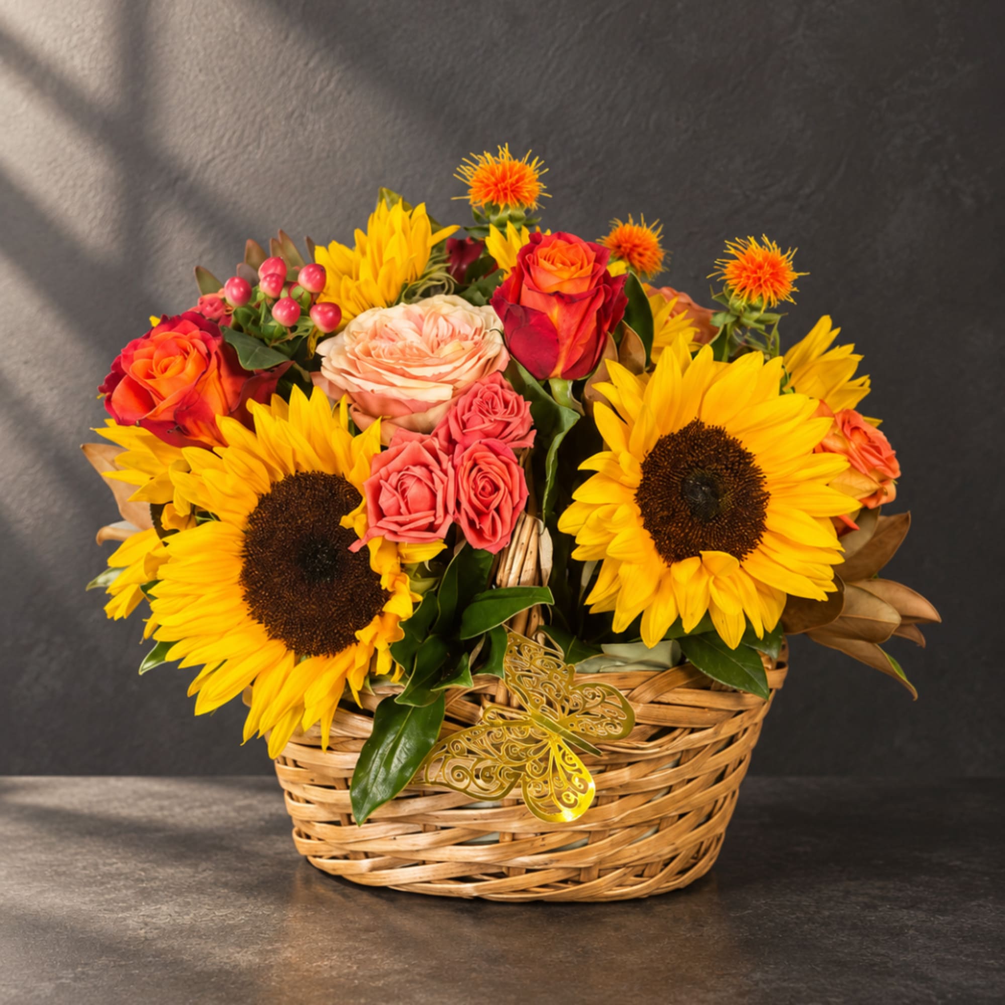 Basket arrangement with sunflowers, roses, and small orange blooms