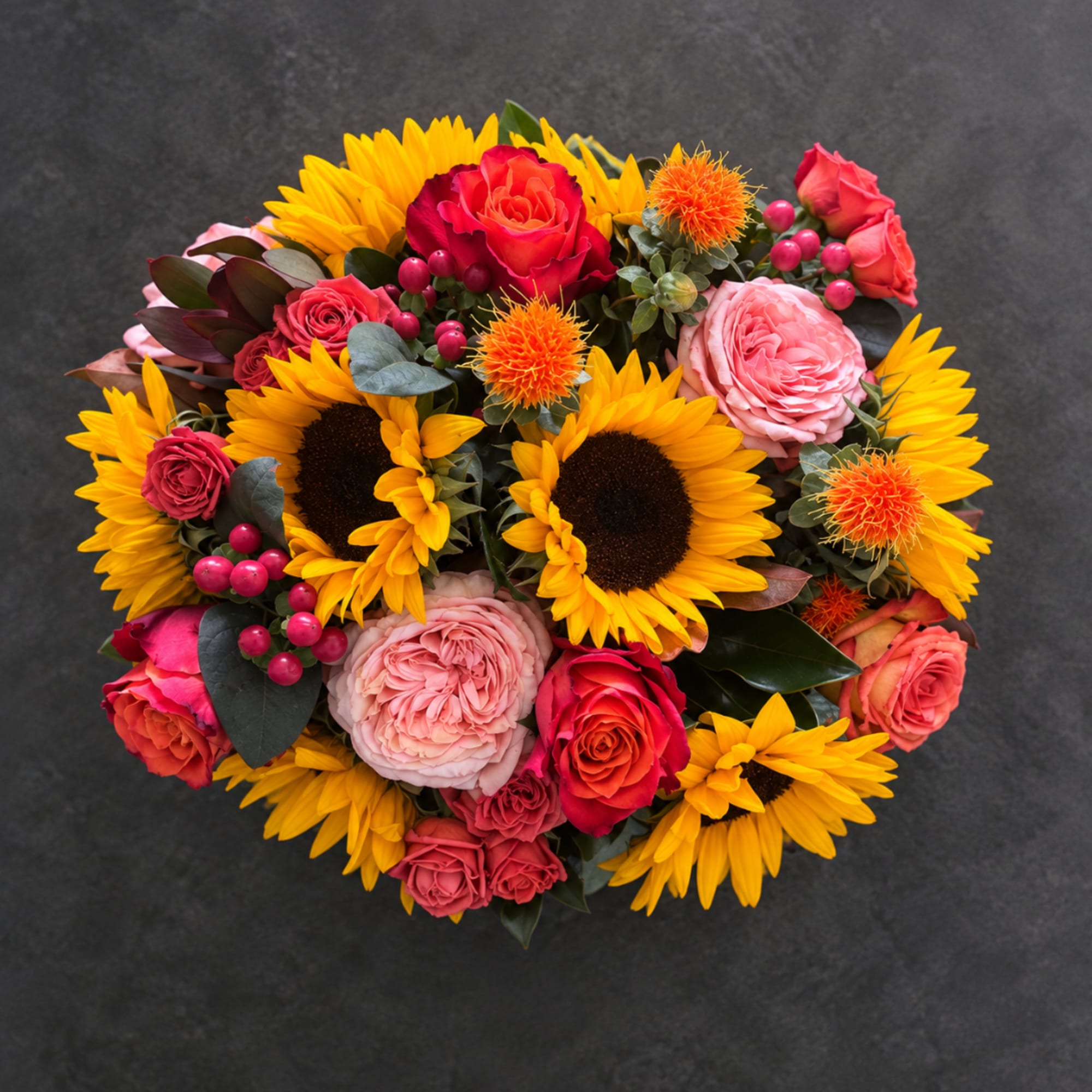 Round bouquet with sunflowers, pink roses, and orange accents