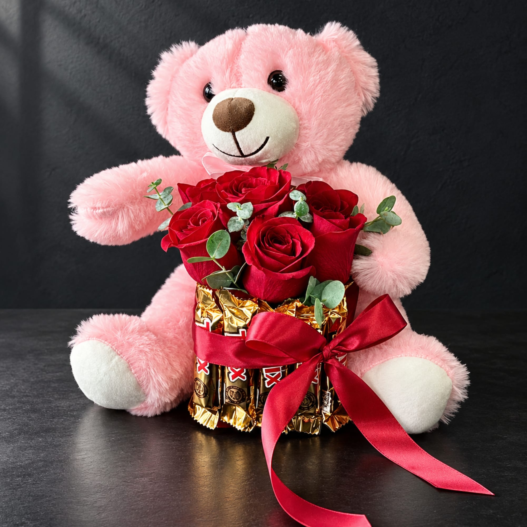 Pink teddy bear holding red roses and chocolate bars with a red ribbon