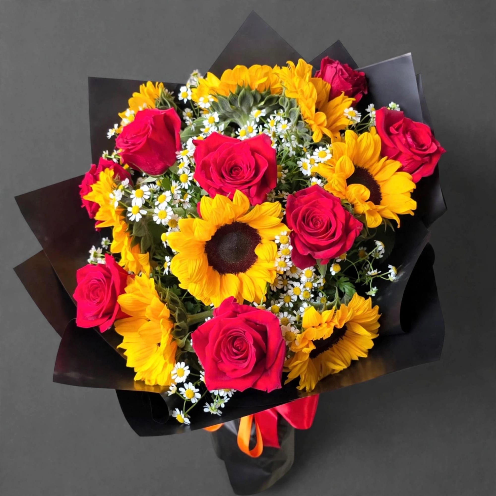 Bouquet of red roses and yellow sunflowers with small white daisies