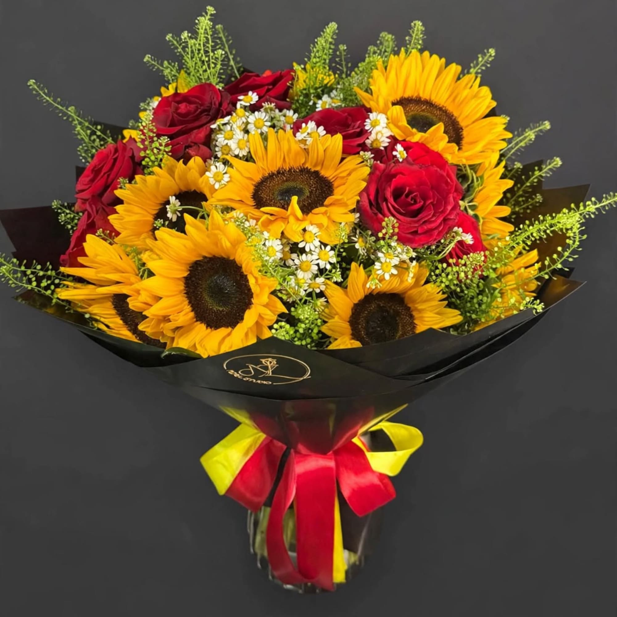 Bouquet of sunflowers and red roses wrapped in black paper with a ribbon