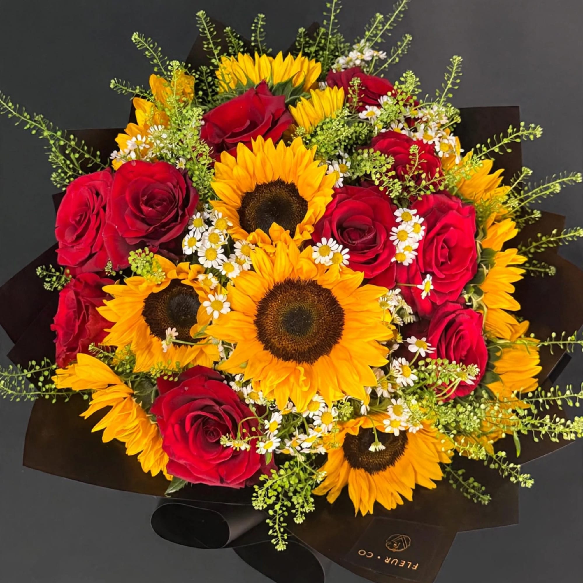 Bouquet of red roses and sunflowers wrapped in black paper